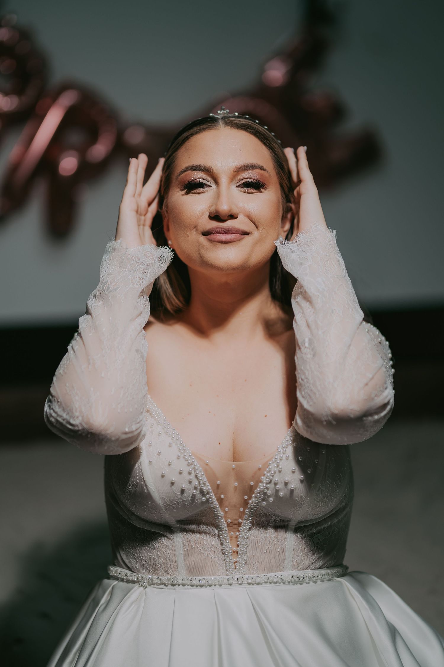 Radiant bride in a deep V-neck beaded wedding gown adjusting her tiara with a joyful smile. Epicu Fotograf Drobeta-Turnu Severin