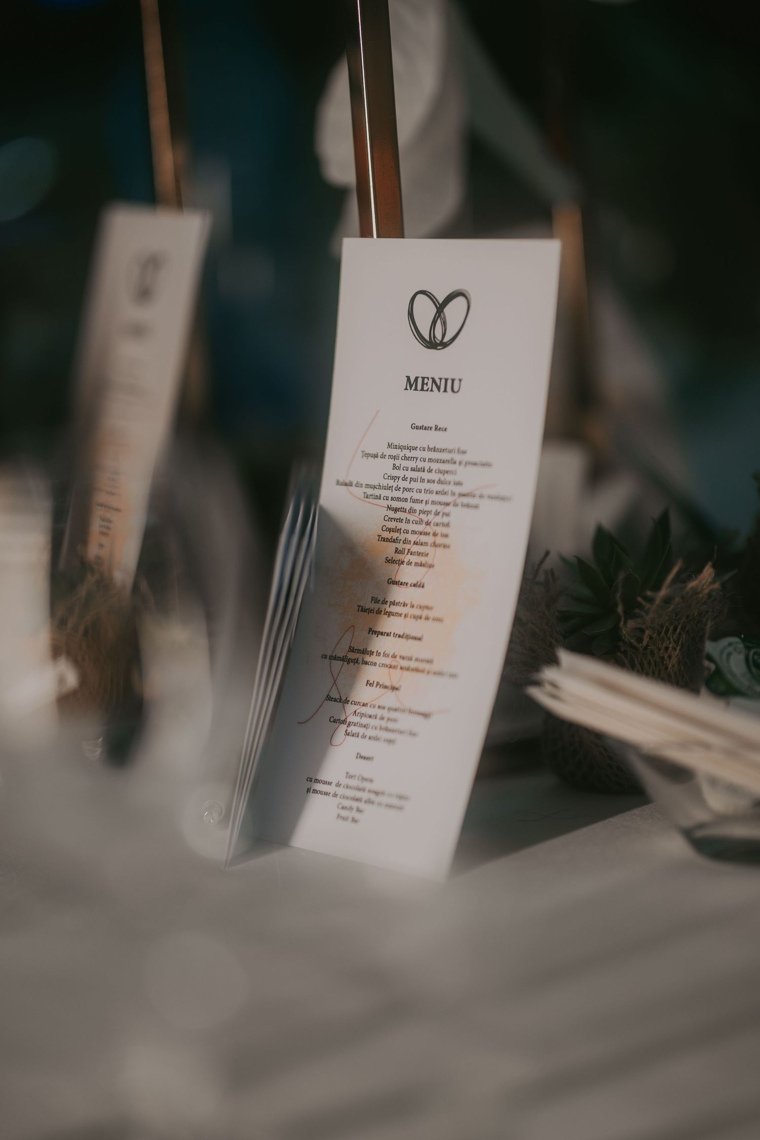 Elegant wedding menu card with heart logo displayed on decorated reception table setting. Epicu Fotograf Drobeta-Turnu Severin