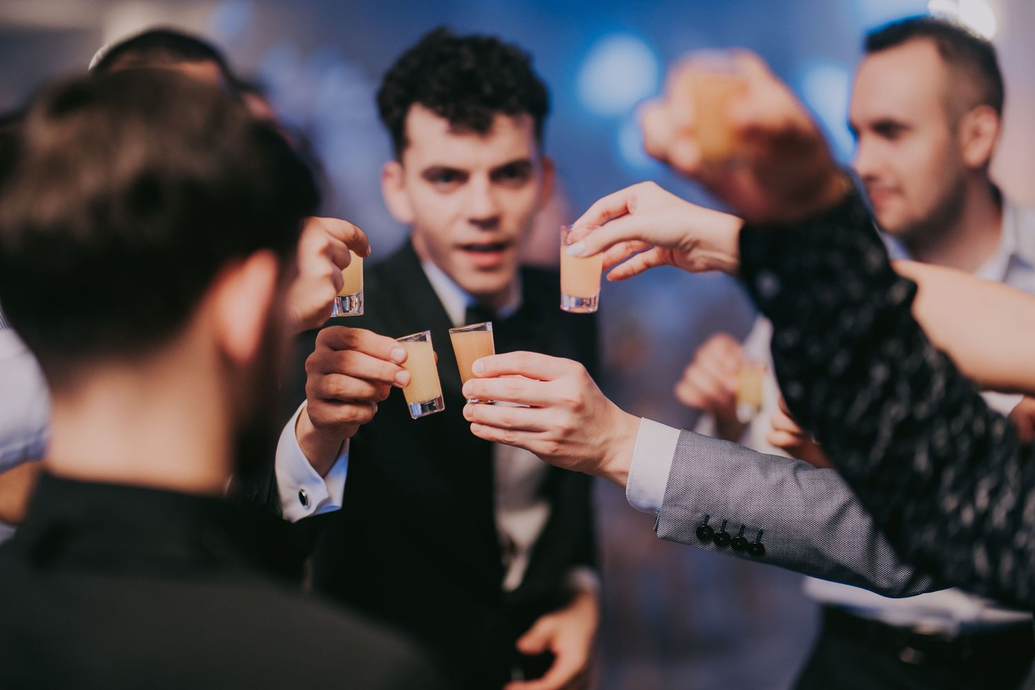 Groom and groomsmen clink small shot glasses together in a celebratory toast at a wedding reception. Epicu Fotograf Drobeta-Turnu Severin