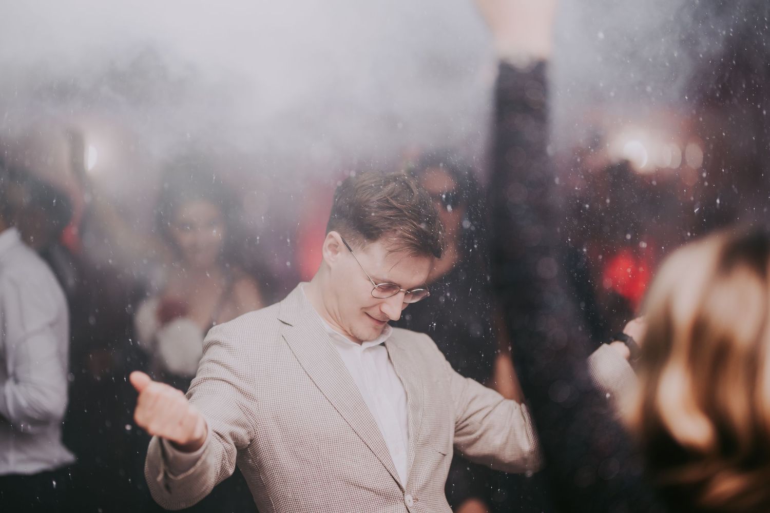 Smiling man in beige suit dancing joyfully on a foggy, crowded wedding reception dance floor. Epicu Fotograf Drobeta-Turnu Severin