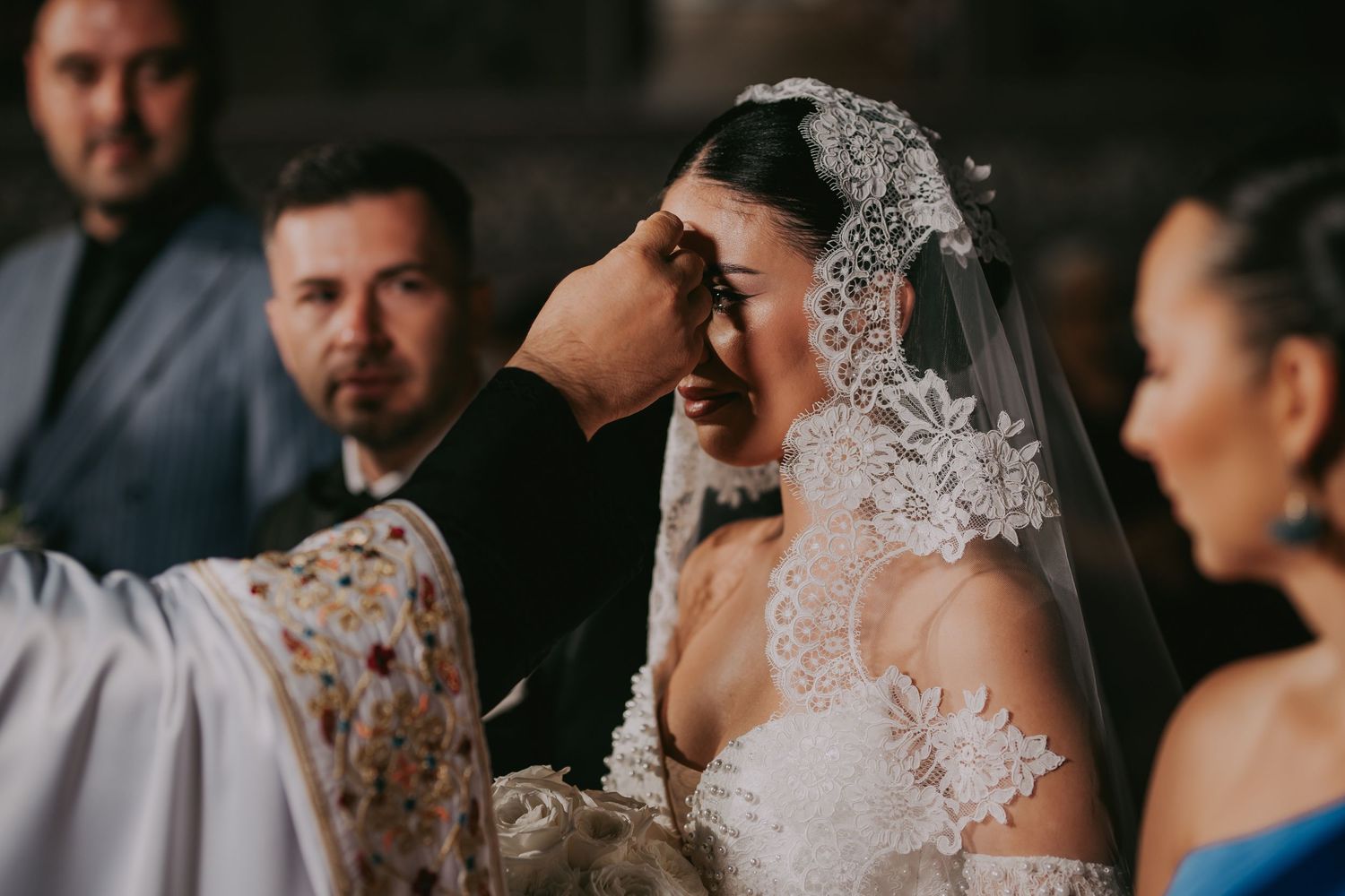 Priest anointing bride with holy oil during traditional Orthodox Christian wedding ceremony inside ornate church.
