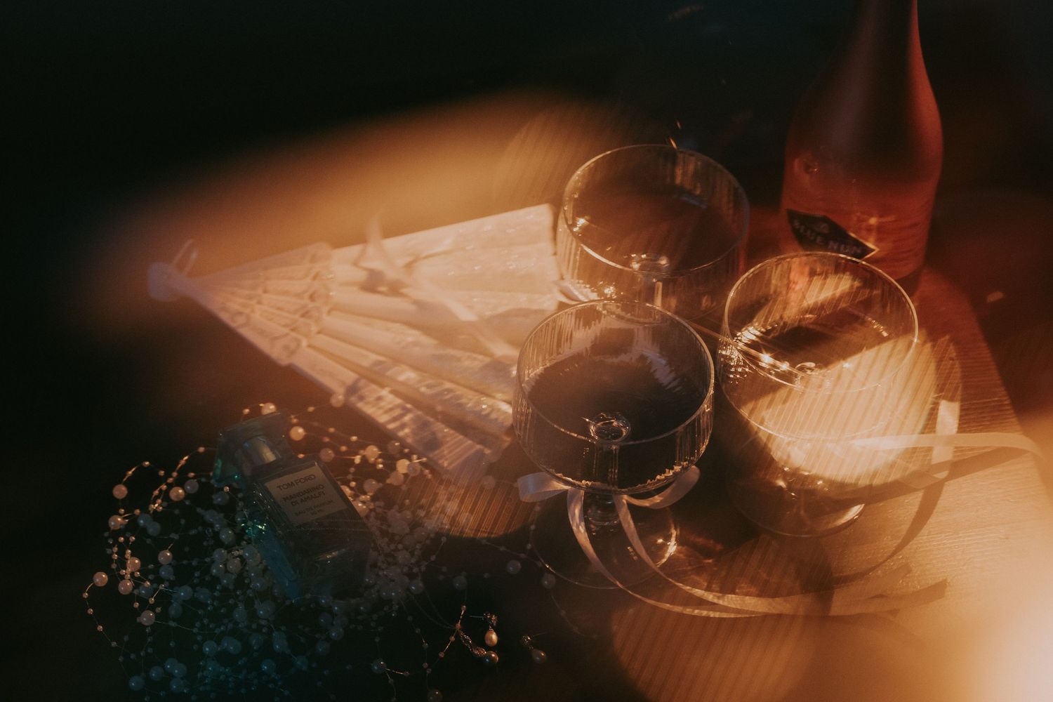 Elegant wine glasses and red wine bottle on a table bathed in warm golden light.