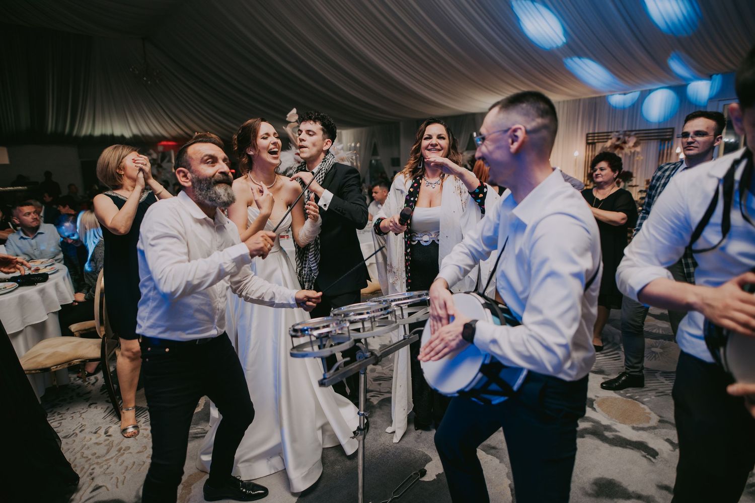Bride and groom dancing joyfully with guests around a steel drum at a lively wedding party. Epicu Fotograf Drobeta-Turnu Severin