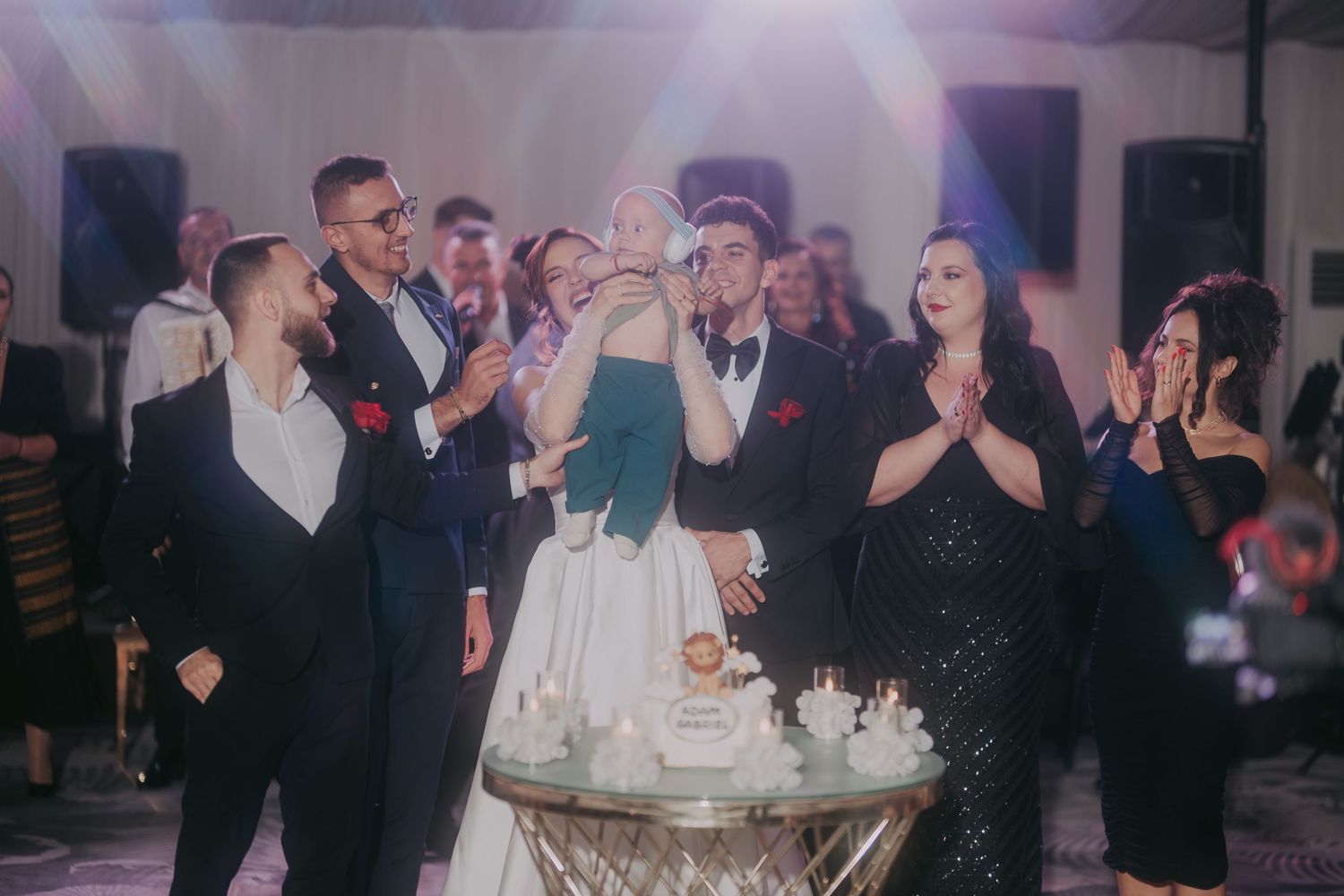 Wedding guests gather around couple cutting cake at elegant reception with chandeliers and festive lighting. Epicu Fotograf Drobeta-Turnu Se