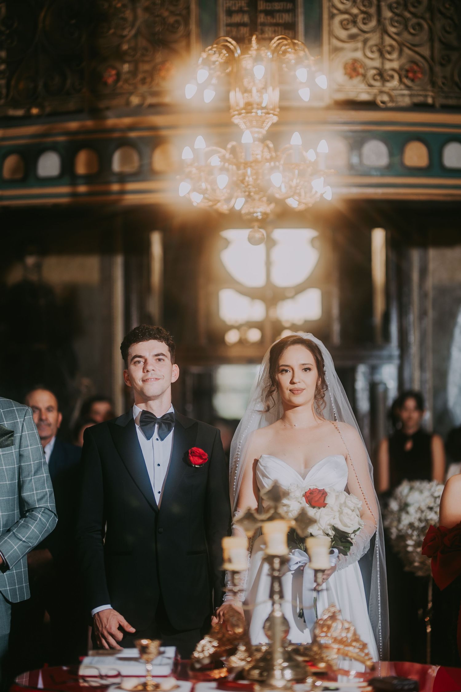 Bride and groom stand together at ornate church altar beneath golden chandelier during ceremony. Epicu Fotograf Drobeta-Turnu Severin