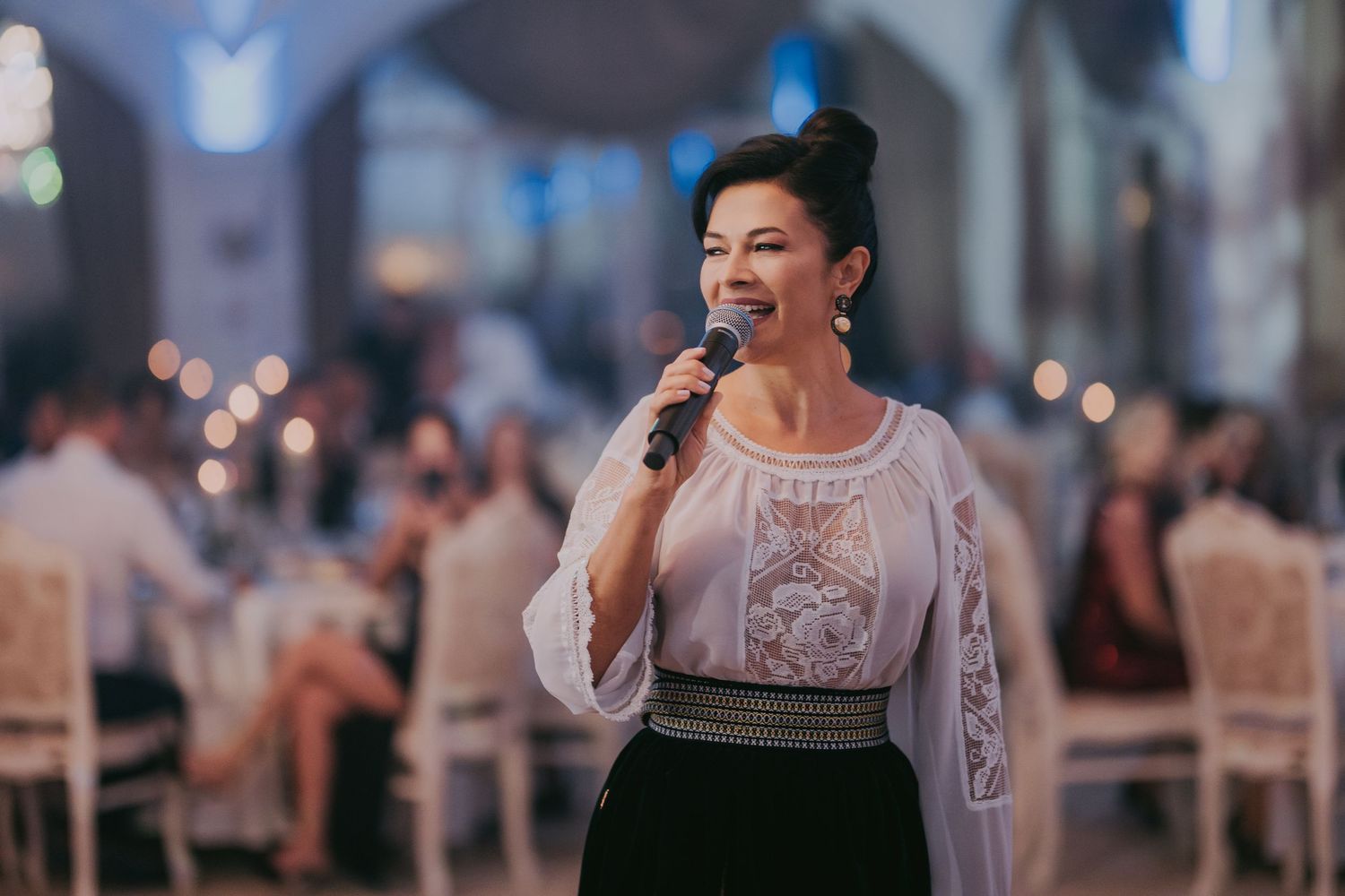 Woman in traditional Romanian blouse performing with microphone at a wedding reception celebration. Epicu Fotograf Drobeta-Turnu Severin