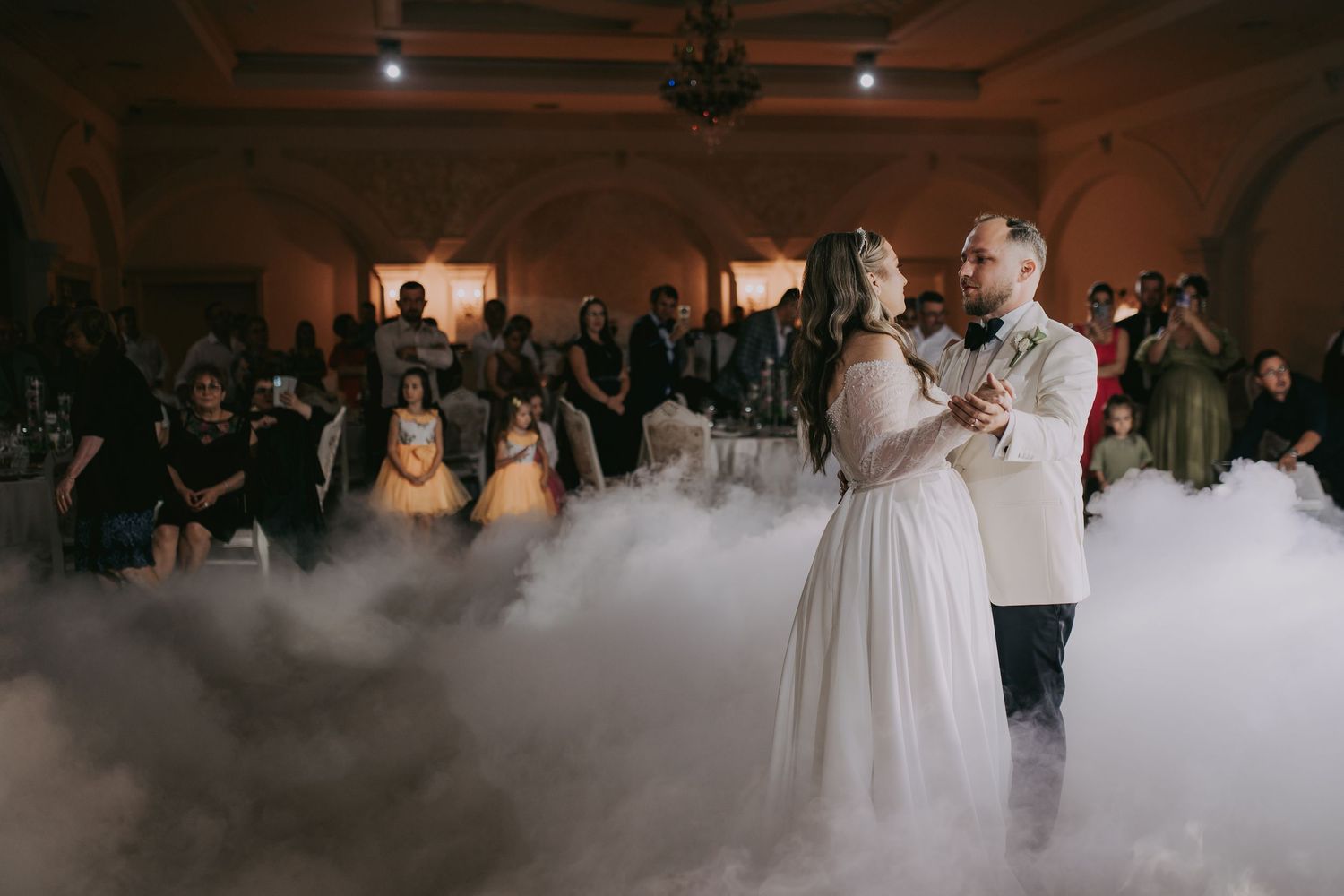 Bride and groom sharing first dance surrounded by dramatic fog on a grand ballroom dance floor. Epicu Fotograf Drobeta-Turnu Severin