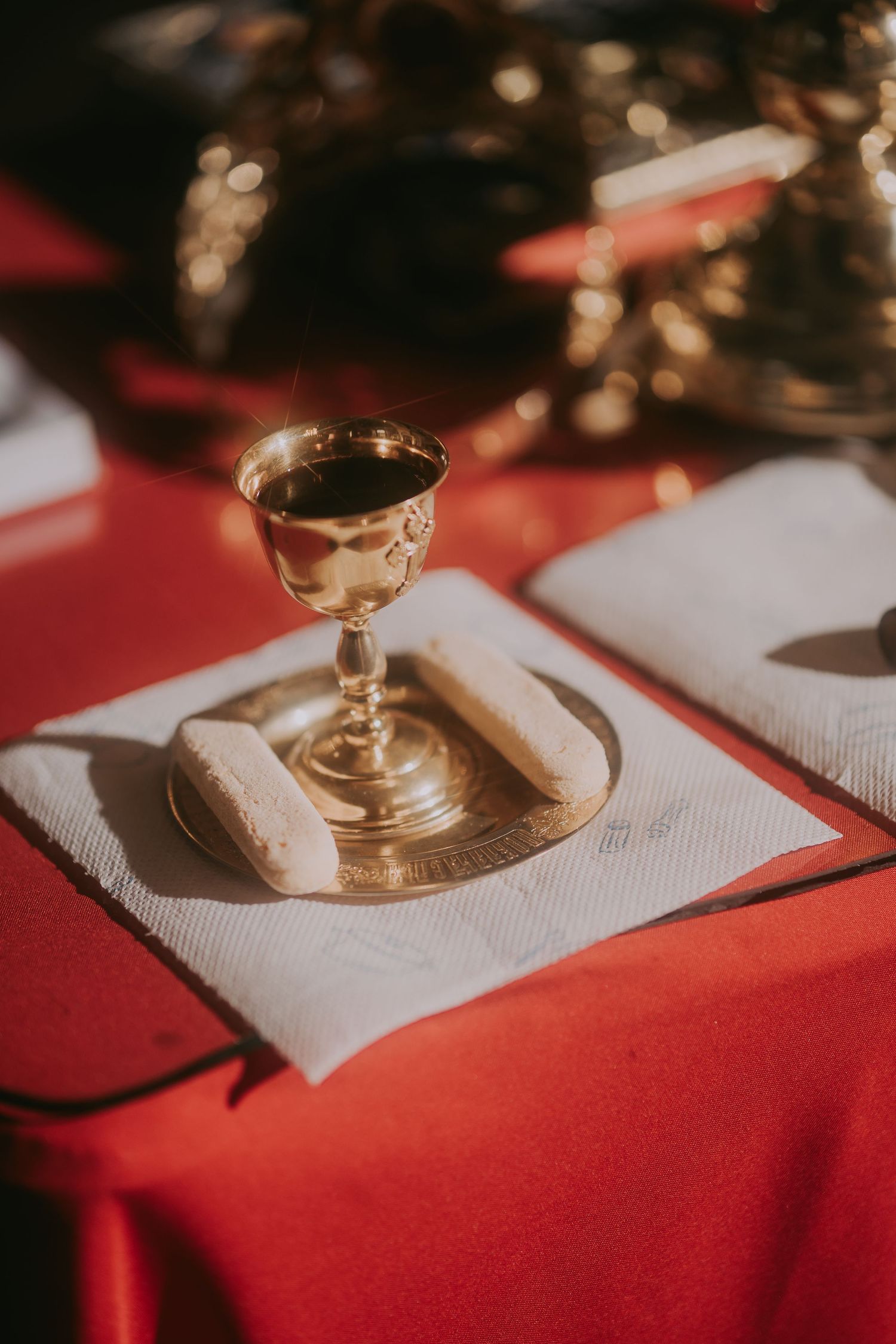 Golden communion chalice with bread on a white napkin atop a red cloth altar table. Epicu Fotograf Drobeta-Turnu Severin