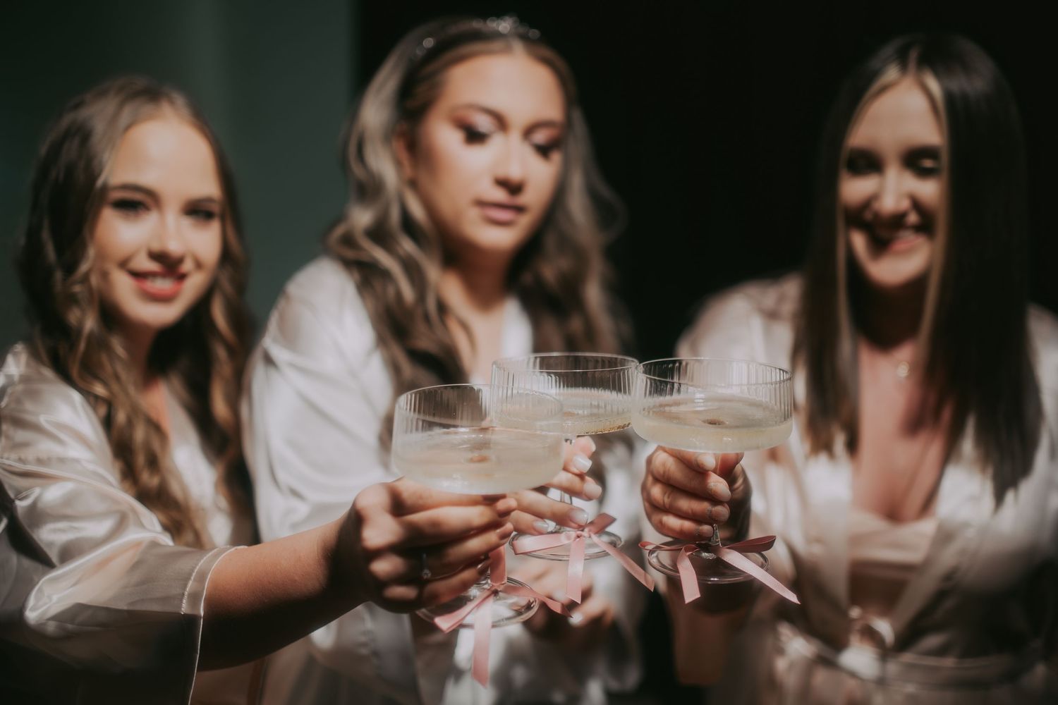 Three bridesmaids in white robes toasting with champagne glasses at a bachelorette party celebration. Epicu Fotograf Drobeta-Turnu Severin