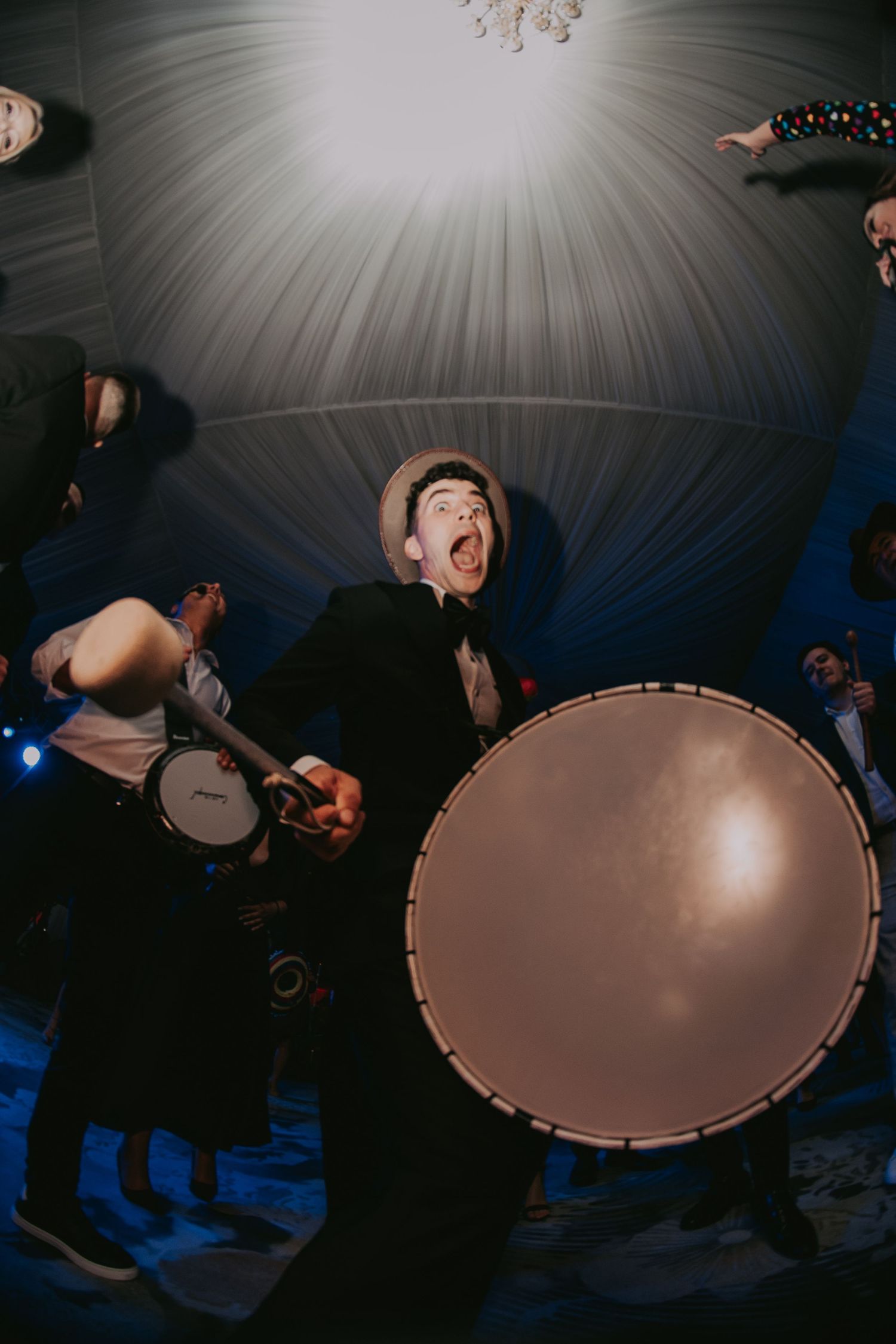 Energetic drummer performing at a lively wedding reception party under dramatic tent lighting. Epicu Fotograf Drobeta-Turnu Severin
