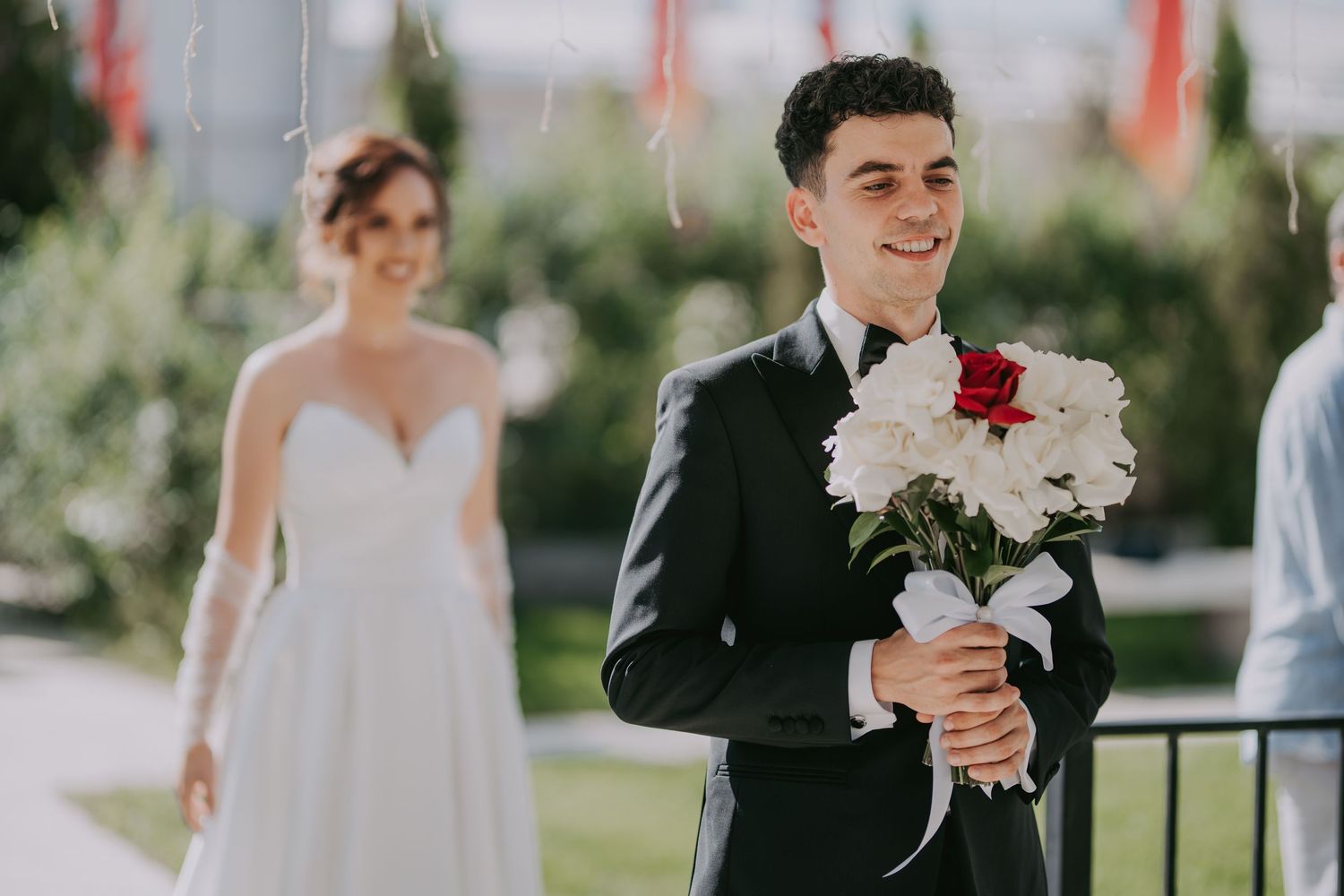 Groom smiling holding bouquet as bride in white gown approaches during first look moment. Epicu Fotograf Drobeta-Turnu Severin