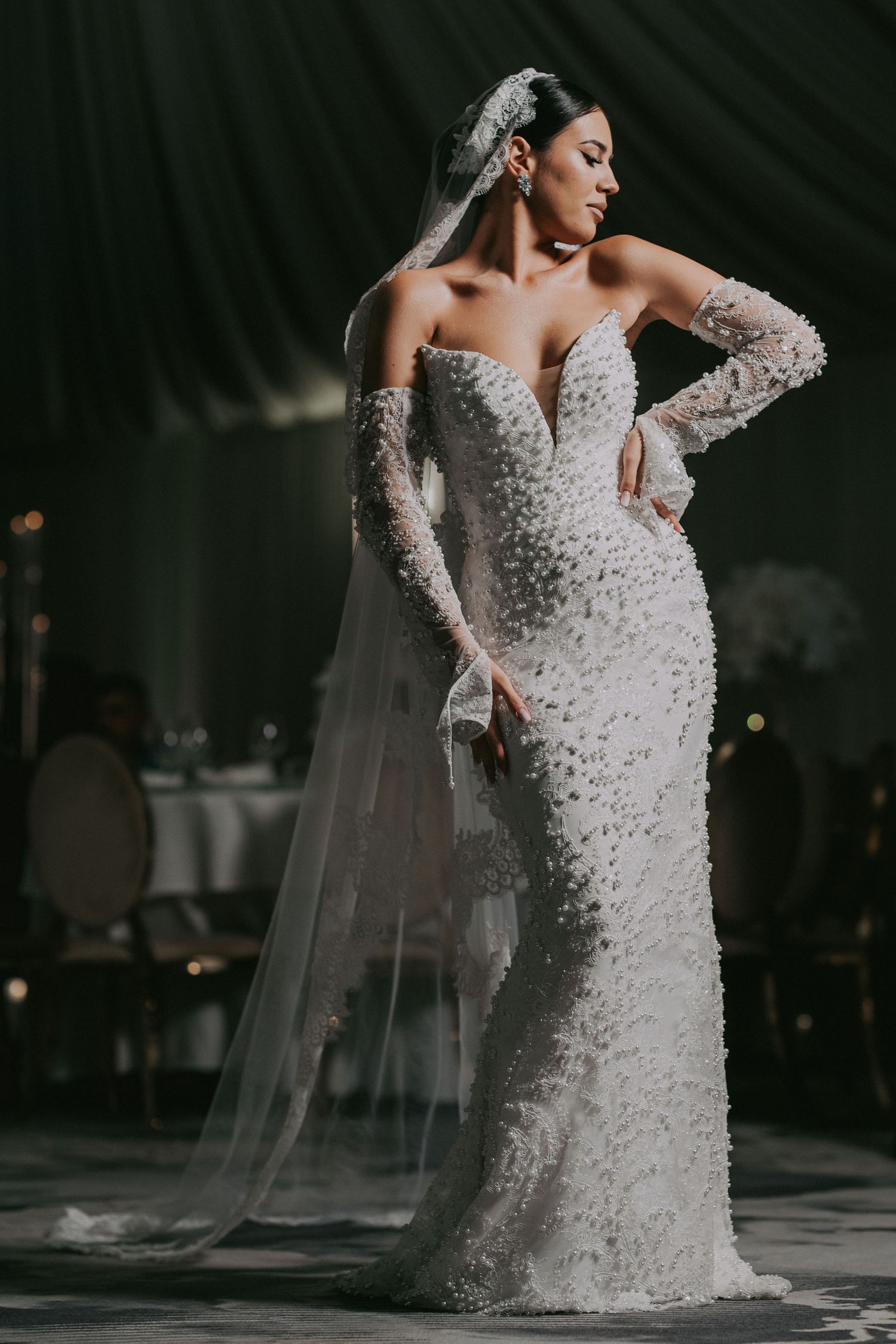Bride in stunning floral applique mermaid wedding dress with cathedral veil poses elegantly.