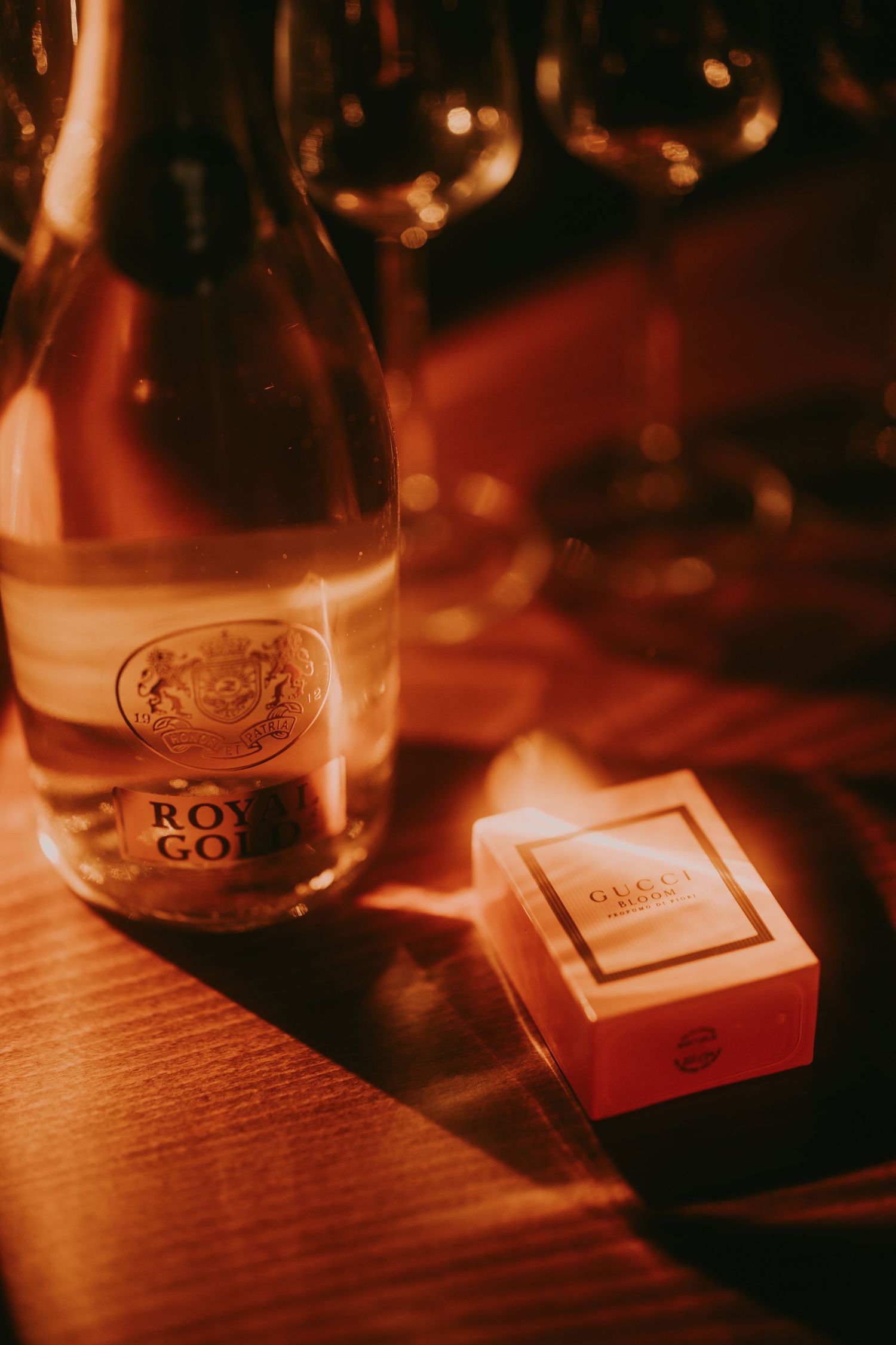 Royal Gold champagne bottle beside a Gucci perfume box in warm moody lighting. Epicu Fotograf Drobeta-Turnu Severin