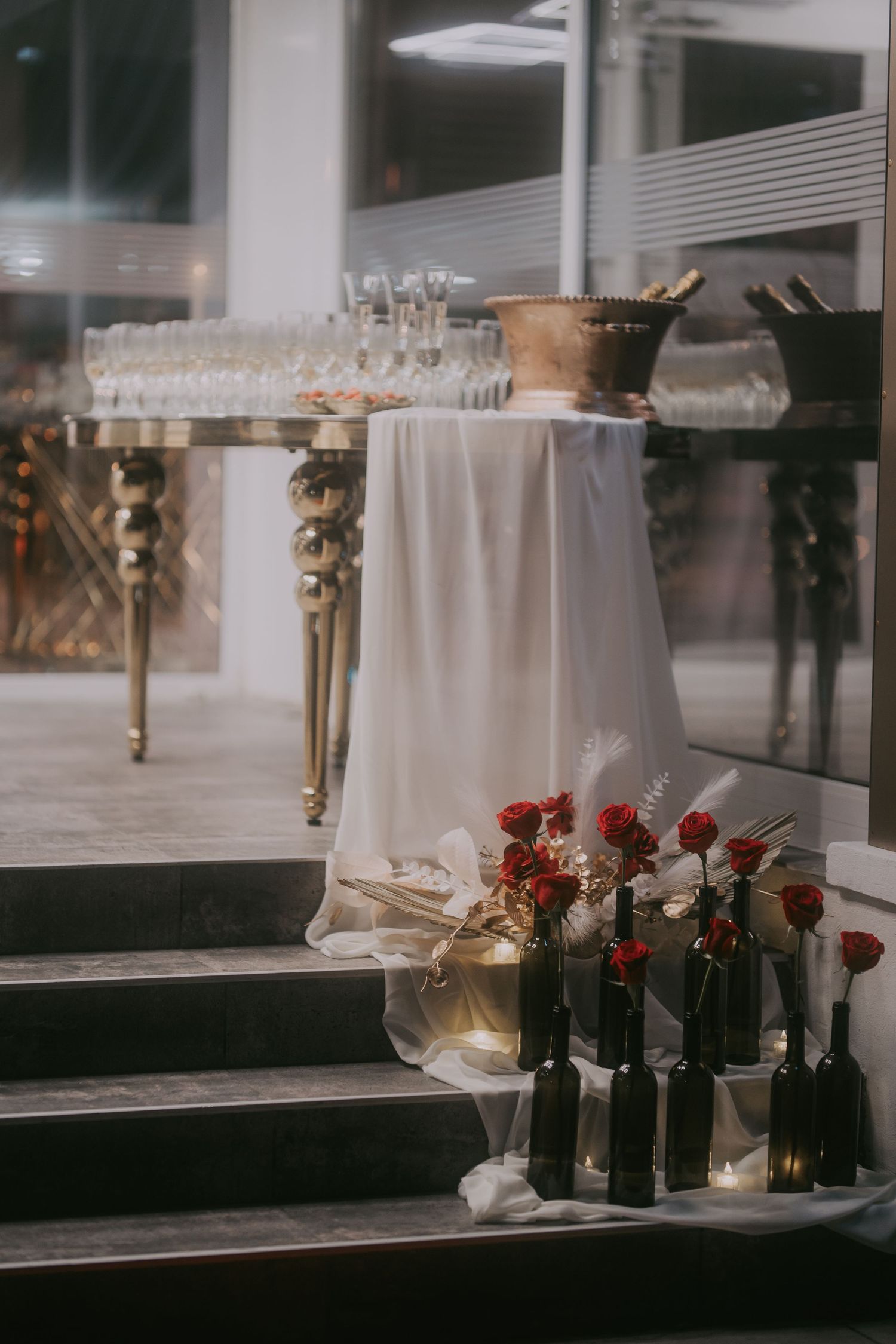 Wedding champagne table with crystal glasses and red roses in bottles on venue steps. Epicu Fotograf Drobeta-Turnu Severin
