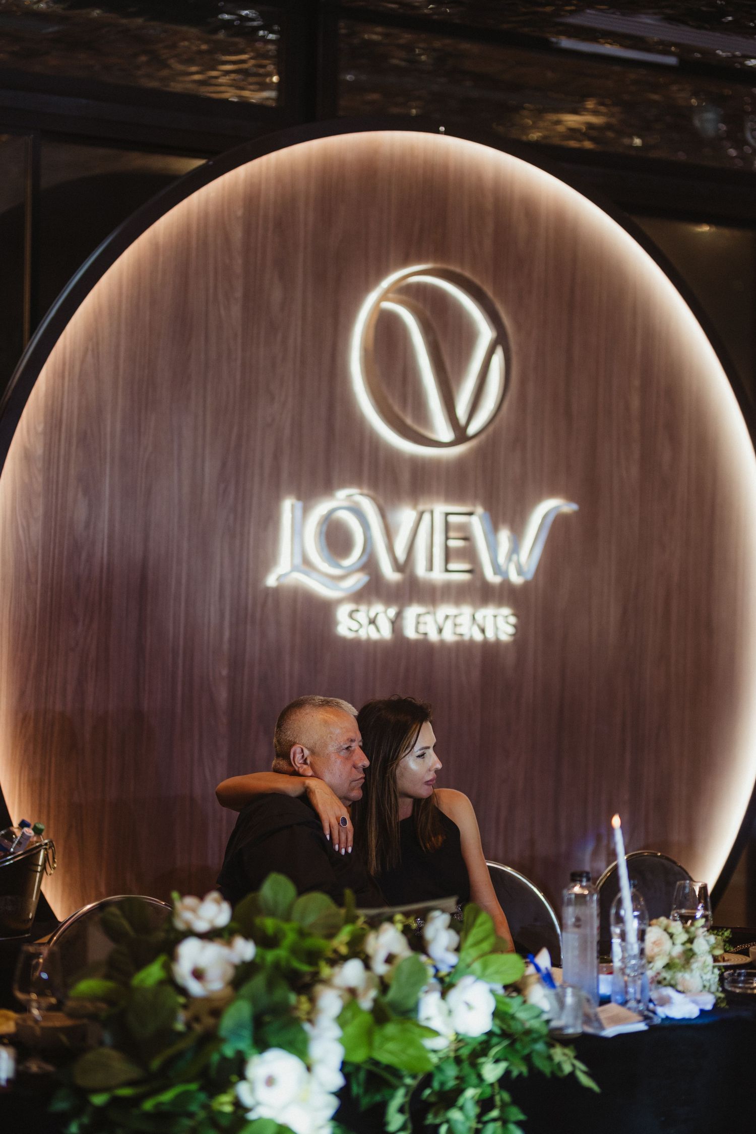 Couple seated at sweetheart table in front of illuminated Loview Sky Events logo backdrop. Epicu Fotograf Drobeta-Turnu Severin