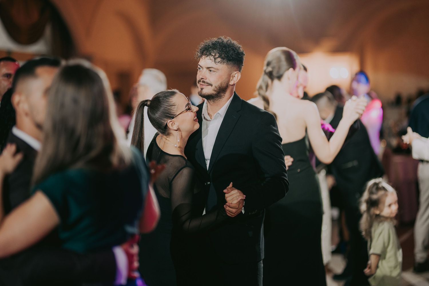 Couple dancing closely at a lively wedding reception in a warmly lit elegant ballroom. Epicu Fotograf Drobeta-Turnu Severin