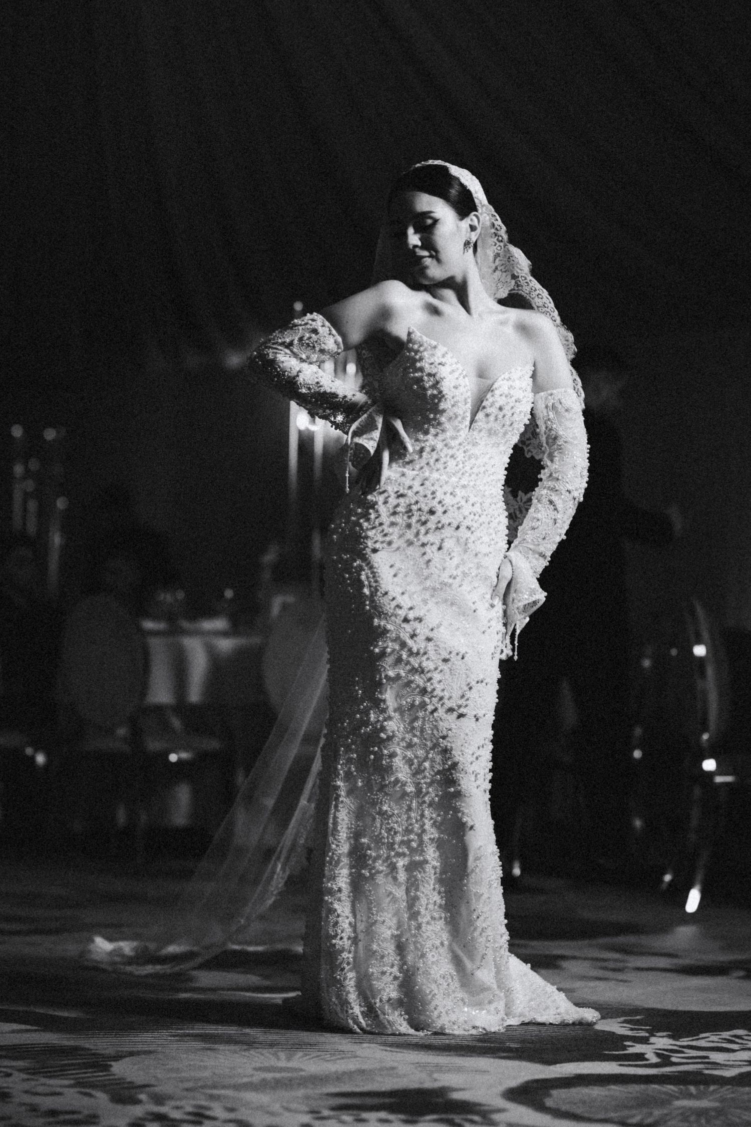 Black and white photo of bride in heavily embellished mermaid gown with long veil.
