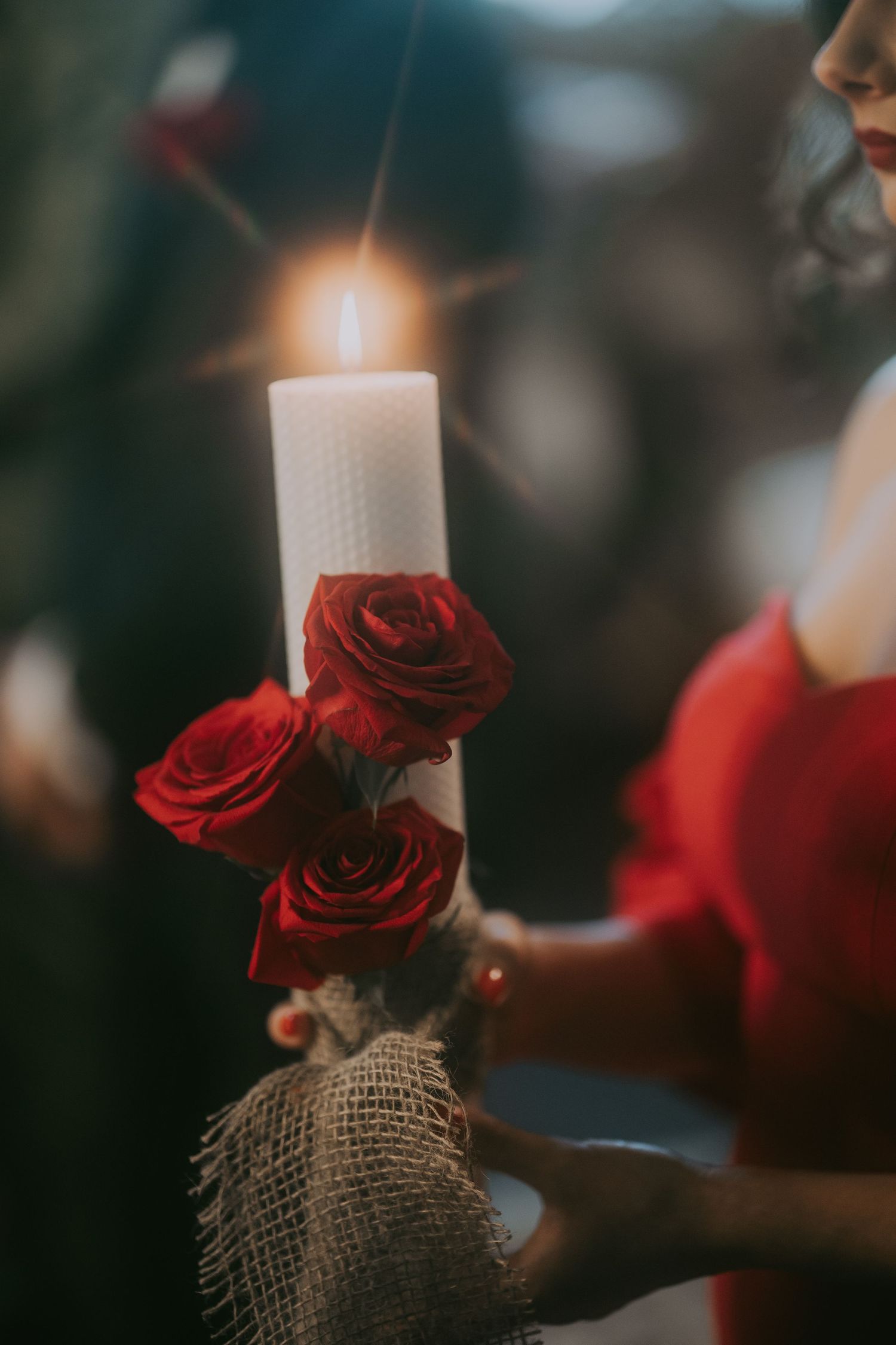 White pillar wedding candle adorned with red roses and burlap held during Orthodox ceremony. Epicu Fotograf Drobeta-Turnu Severin