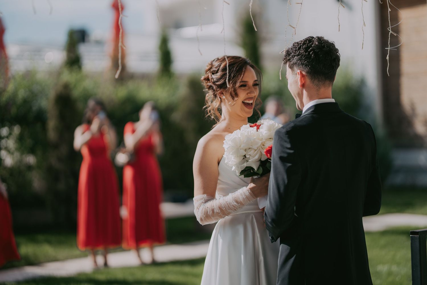 Bride laughing joyfully holding bouquet during outdoor wedding ceremony with bridesmaids behind. Epicu Fotograf Drobeta-Turnu Severin