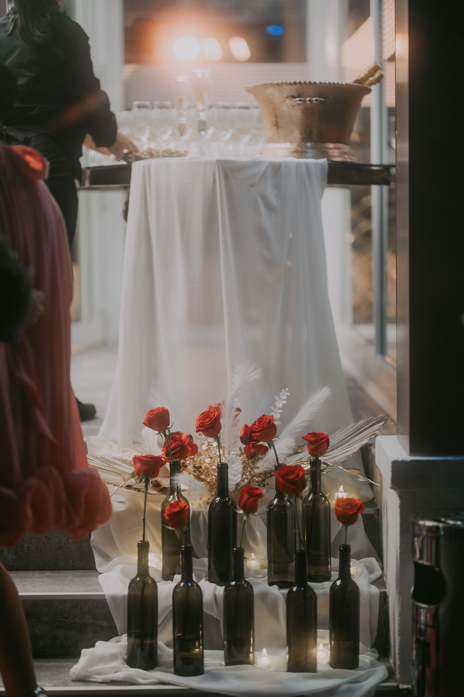 Dark wine bottles with red roses and fairy lights decorating wedding venue entrance steps. Epicu Fotograf Drobeta-Turnu Severin