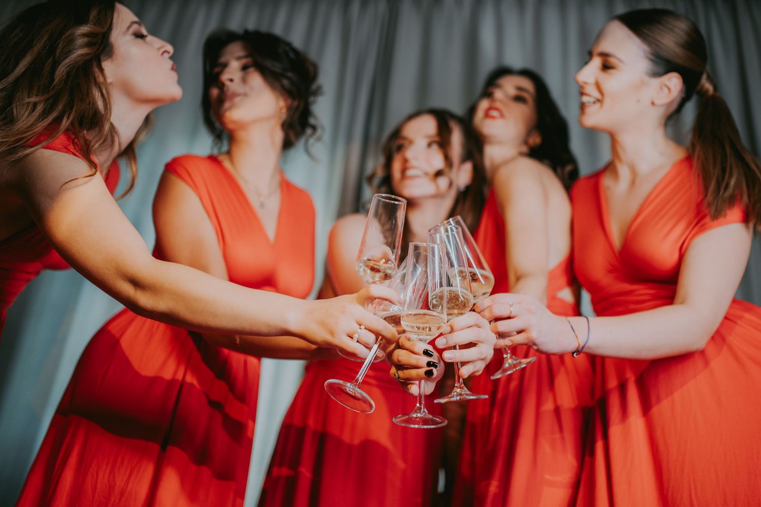 Bridesmaids in red dresses clinking champagne glasses together in a joyful wedding toast. Epicu Fotograf Drobeta-Turnu Severin