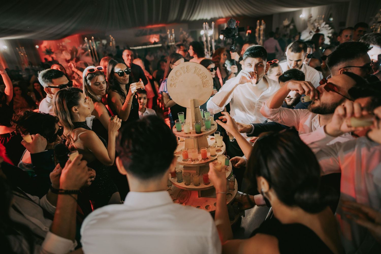 Crowd of wedding guests surrounding a tiered cake at a vibrant nighttime wedding celebration. Epicu Fotograf Drobeta-Turnu Severin