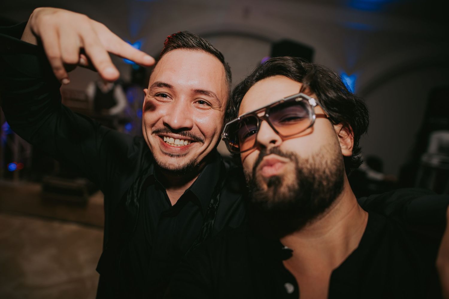 Two men taking a fun selfie at a wedding party, one wearing stylish sunglasses in dark venue. Epicu Fotograf Drobeta-Turnu Severin