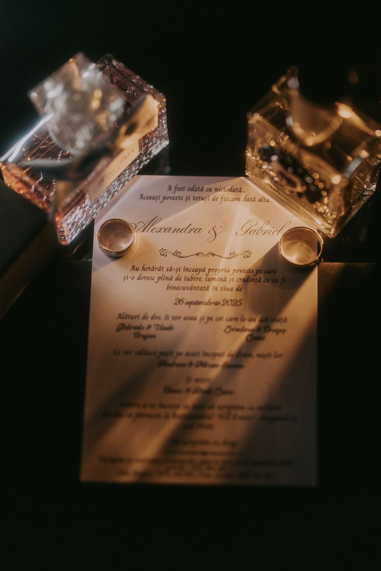 Wedding invitation for Alexandra and Gabriel with gold wedding bands on elegant script-printed card.
