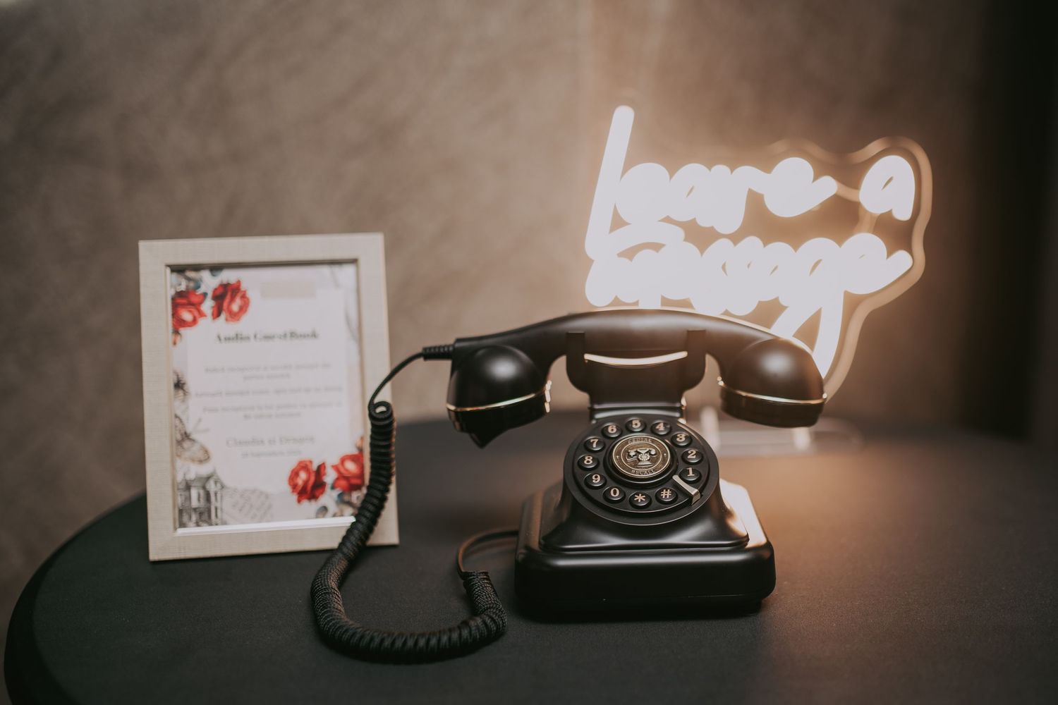 Vintage black rotary telephone with Leave a Message neon sign on dark table at wedding. Epicu Fotograf Drobeta-Turnu Severin