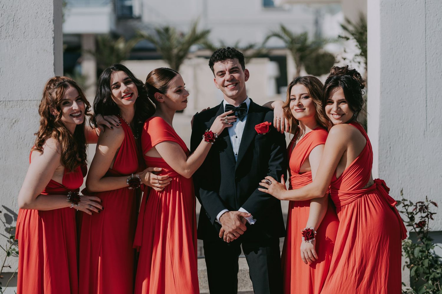 Groom in black tuxedo posing with five bridesmaids in red dresses at a wedding. Epicu Fotograf Drobeta-Turnu Severin