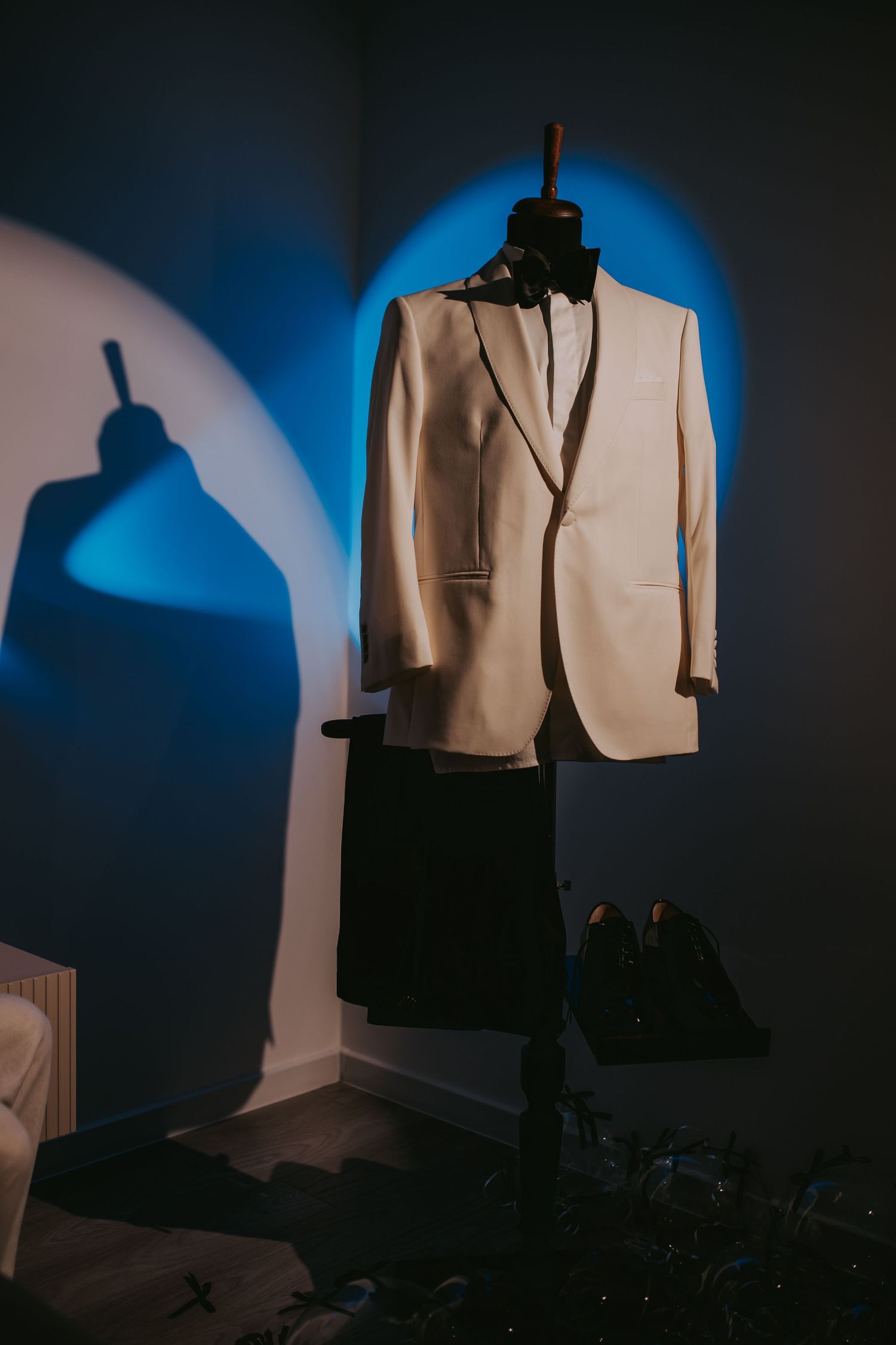 White tuxedo jacket and black trousers displayed on a mannequin with blue ambient lighting. Epicu Fotograf Drobeta-Turnu Severin