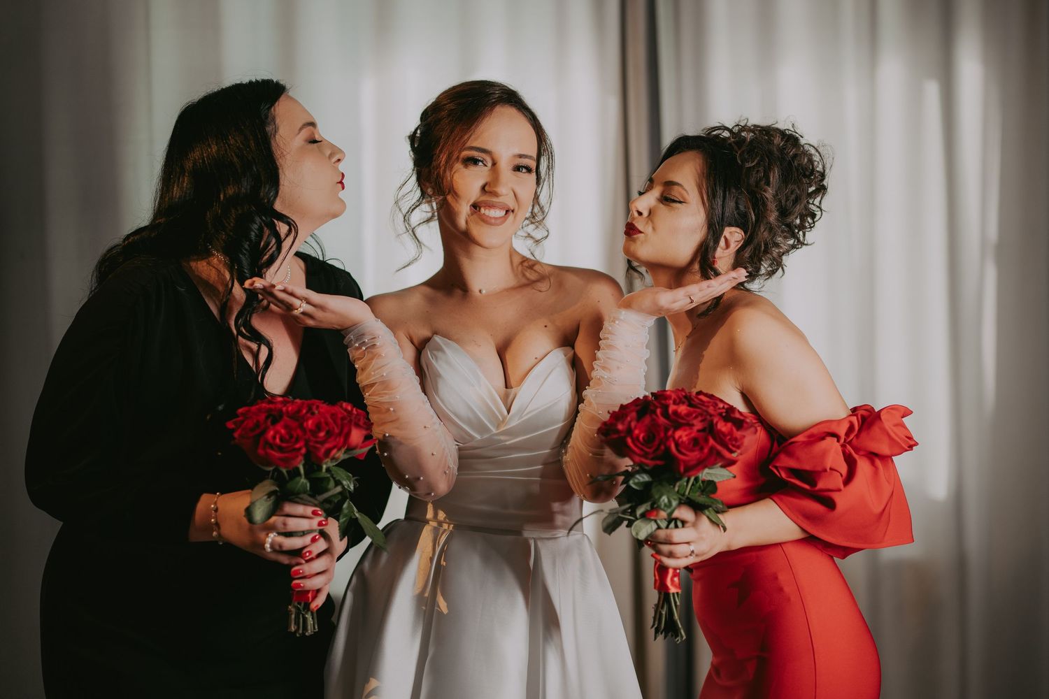 Smiling bride in white gown flanked by two bridesmaids in red holding rose bouquets. Epicu Fotograf Drobeta-Turnu Severin
