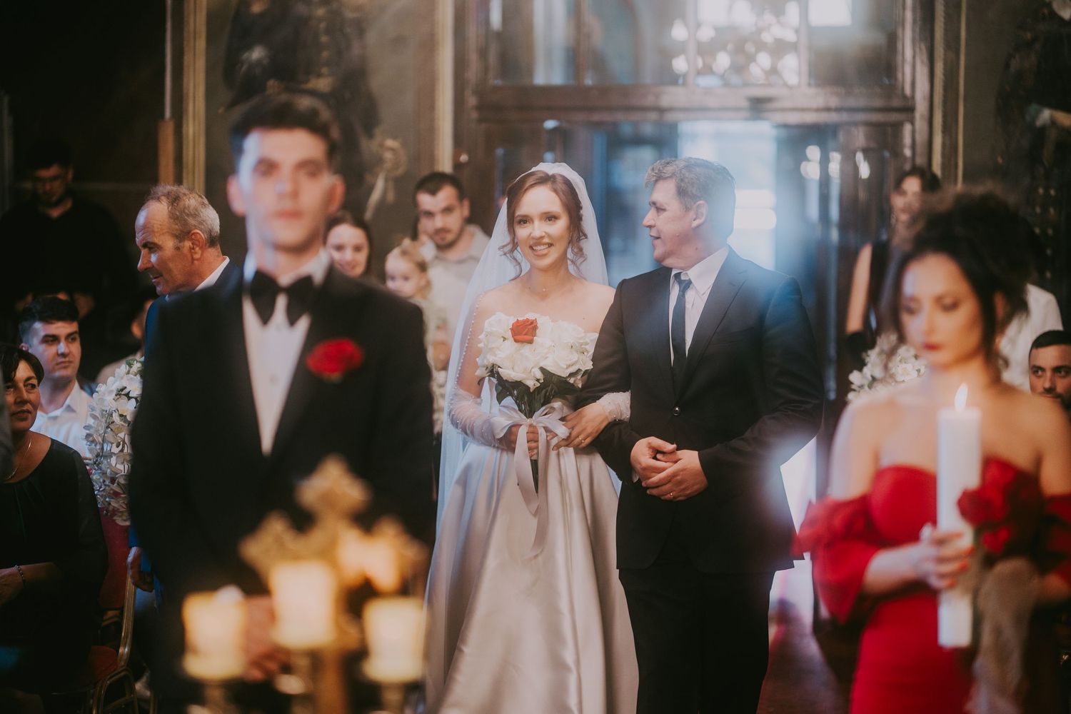 Bride in white gown walks down church aisle with escort during elegant wedding ceremony. Epicu Fotograf Drobeta-Turnu Severin