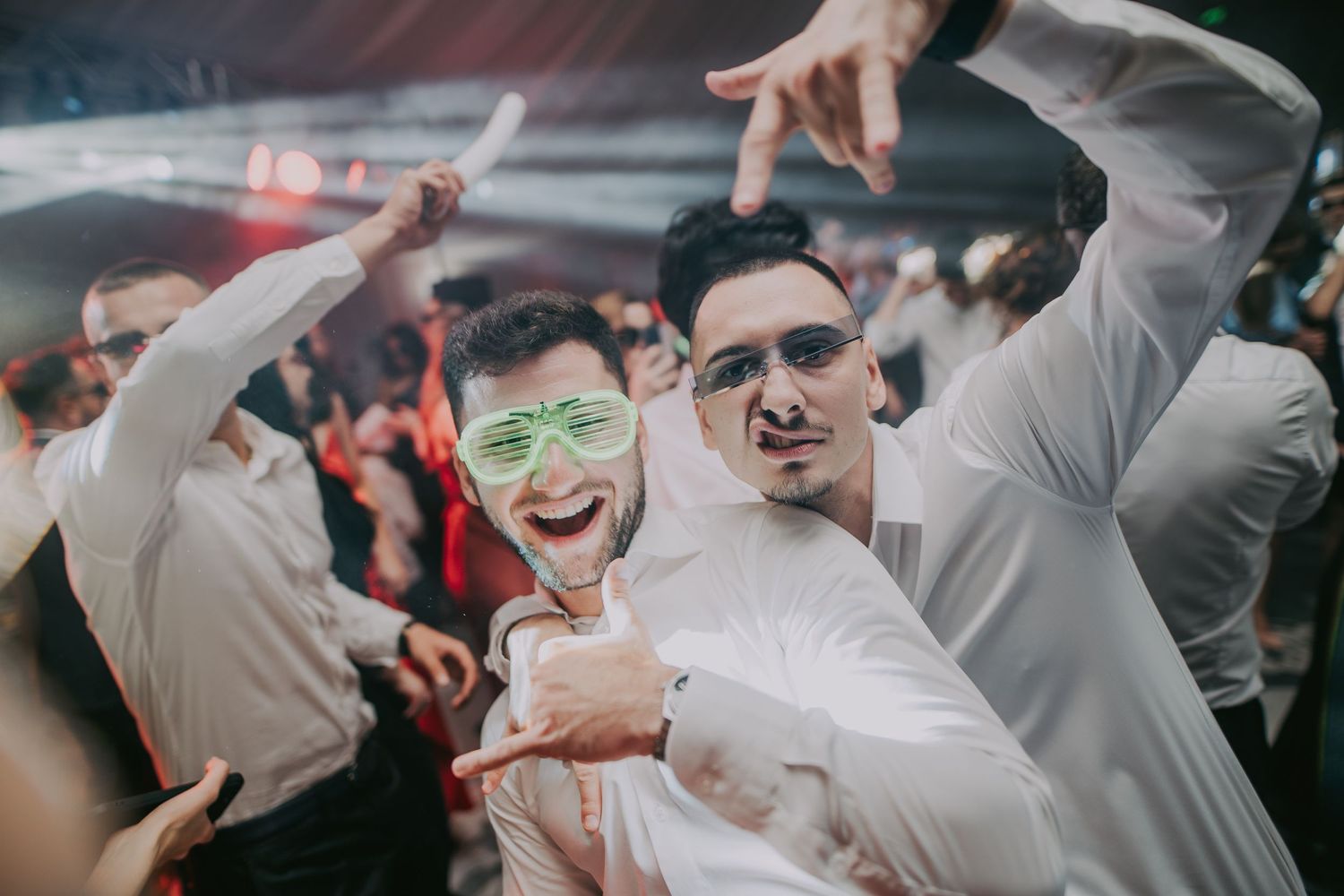 Two young men wearing fun glasses posing and dancing at a lively wedding reception. Epicu Fotograf Drobeta-Turnu Severin