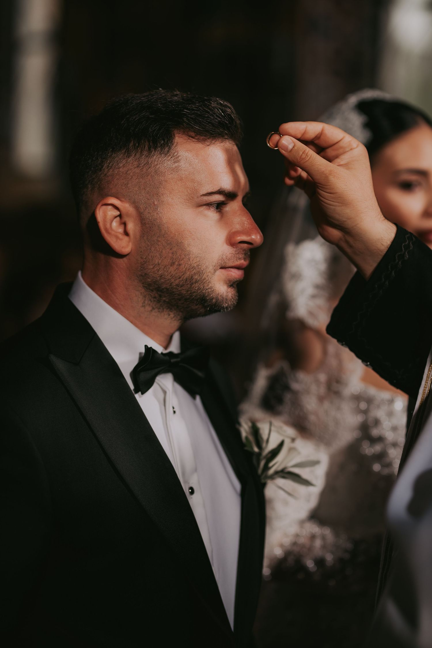 Priest anoints groom with oil during Orthodox wedding ceremony in church.