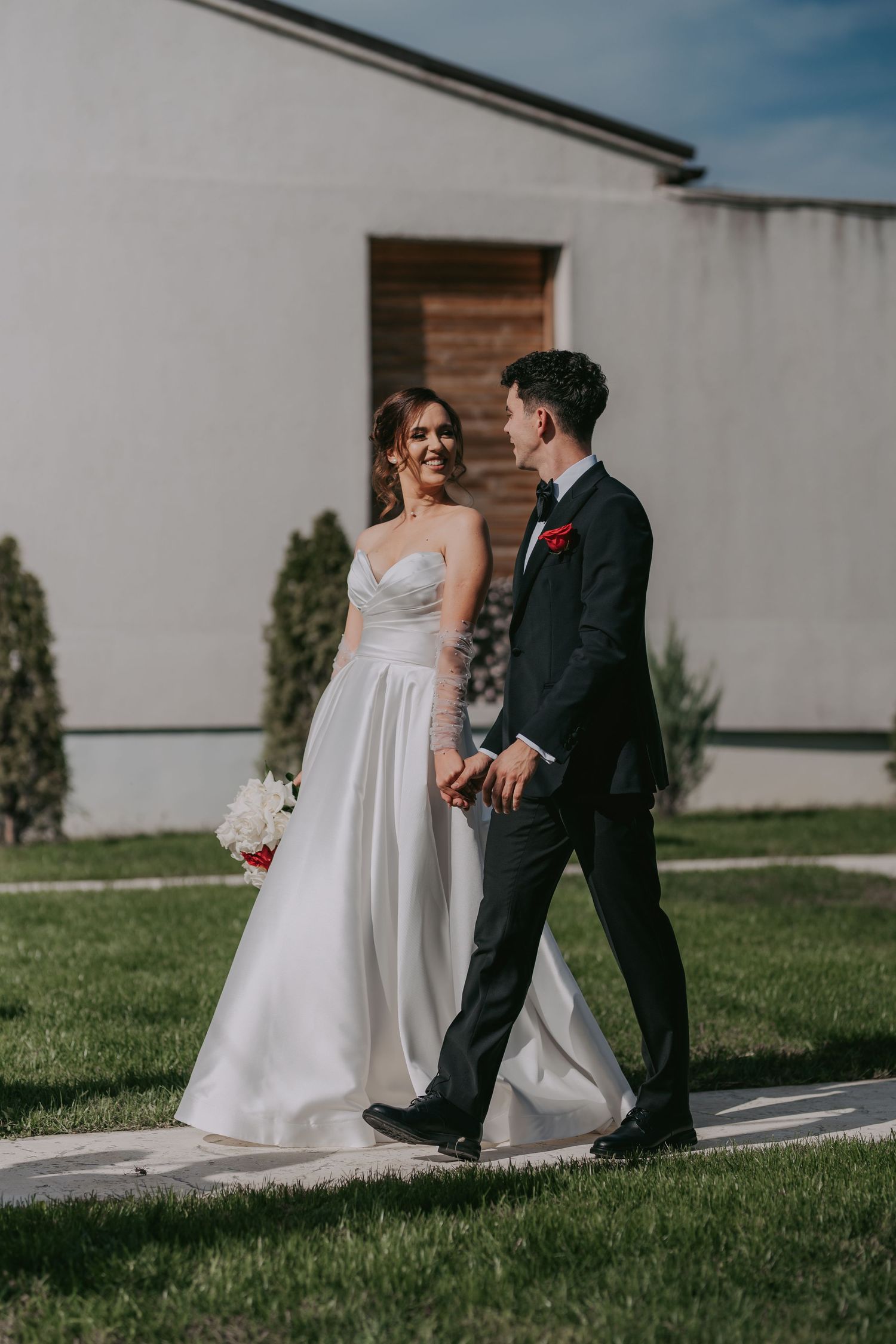 Bride and groom walking hand in hand smiling at each other on their wedding day outdoors. Epicu Fotograf Drobeta-Turnu Severin