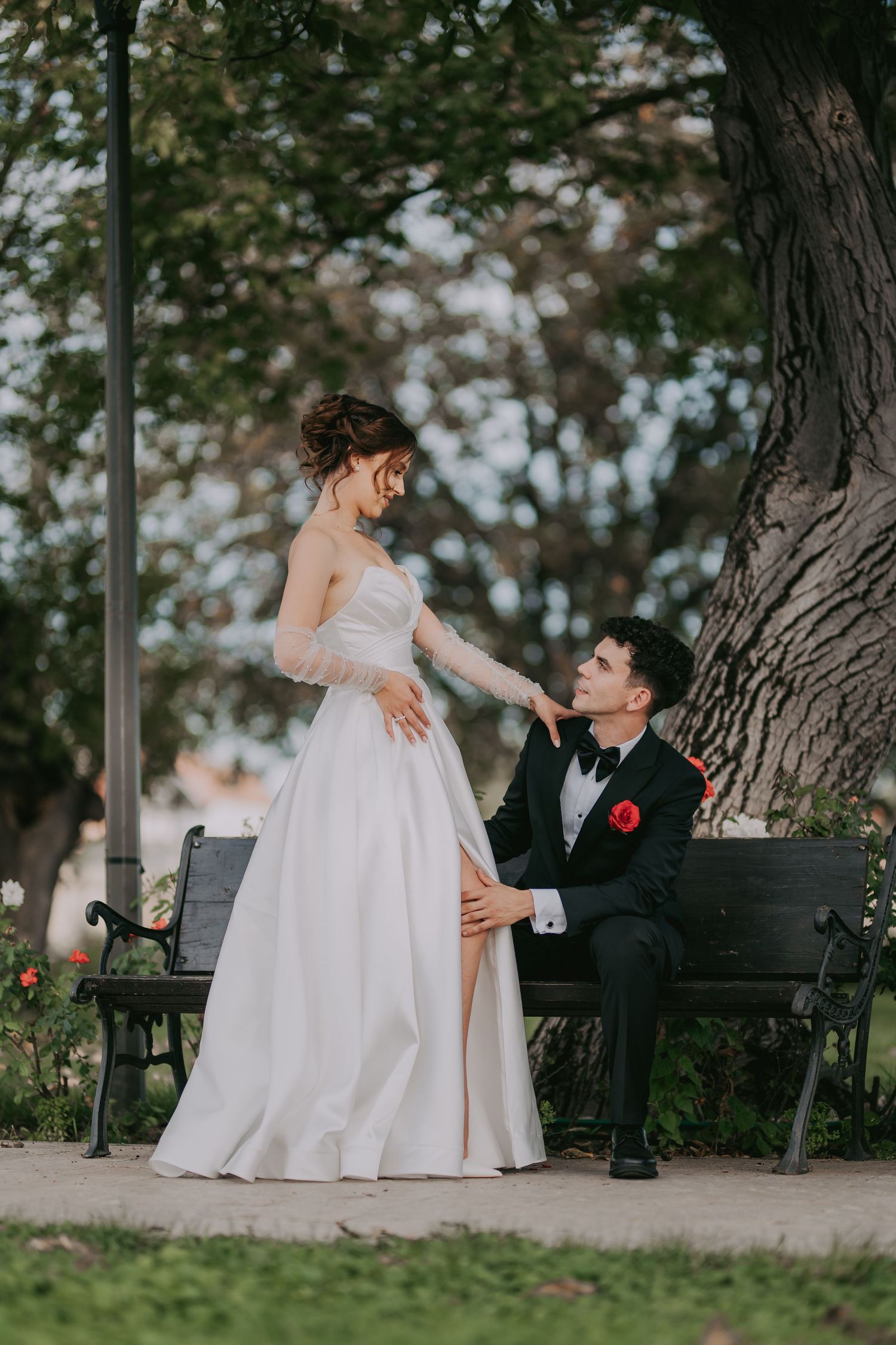 Bride in white gown and groom in black tuxedo sharing a romantic moment on a park bench. Epicu Fotograf Drobeta-Turnu Severin