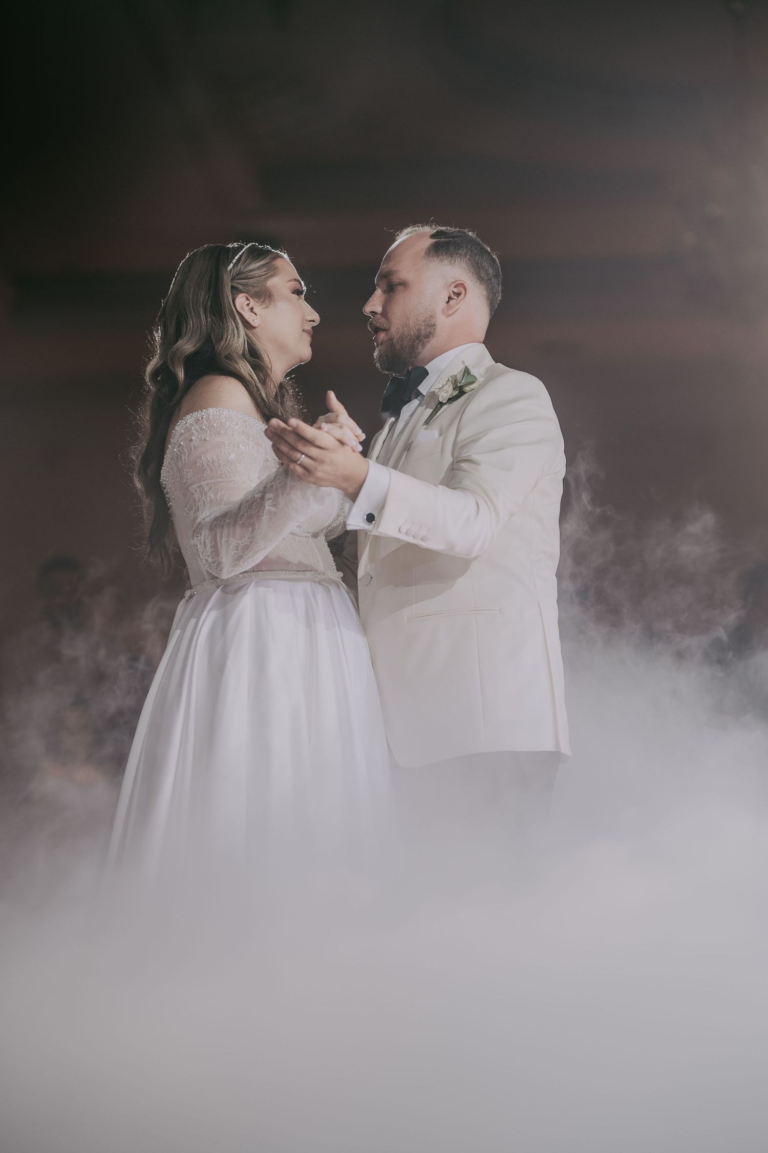 Bride and groom gazing at each other during first dance enveloped in romantic white smoke effect. Epicu Fotograf Drobeta-Turnu Severin