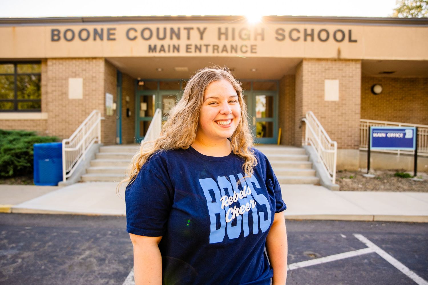 Smiling teenage girl standing in front of Boone County High School main entrance.