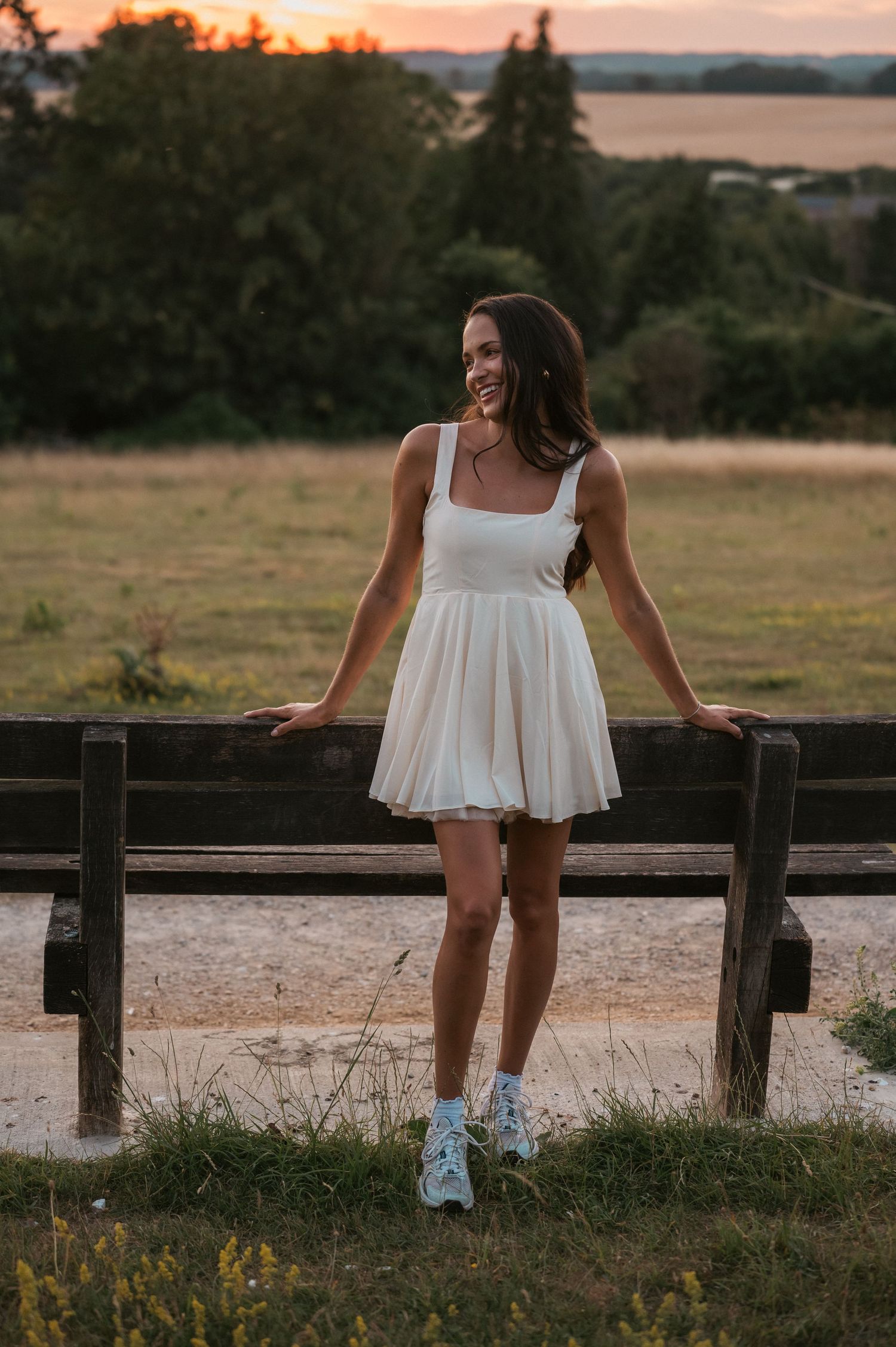 Model in white mini dress in field at sunset