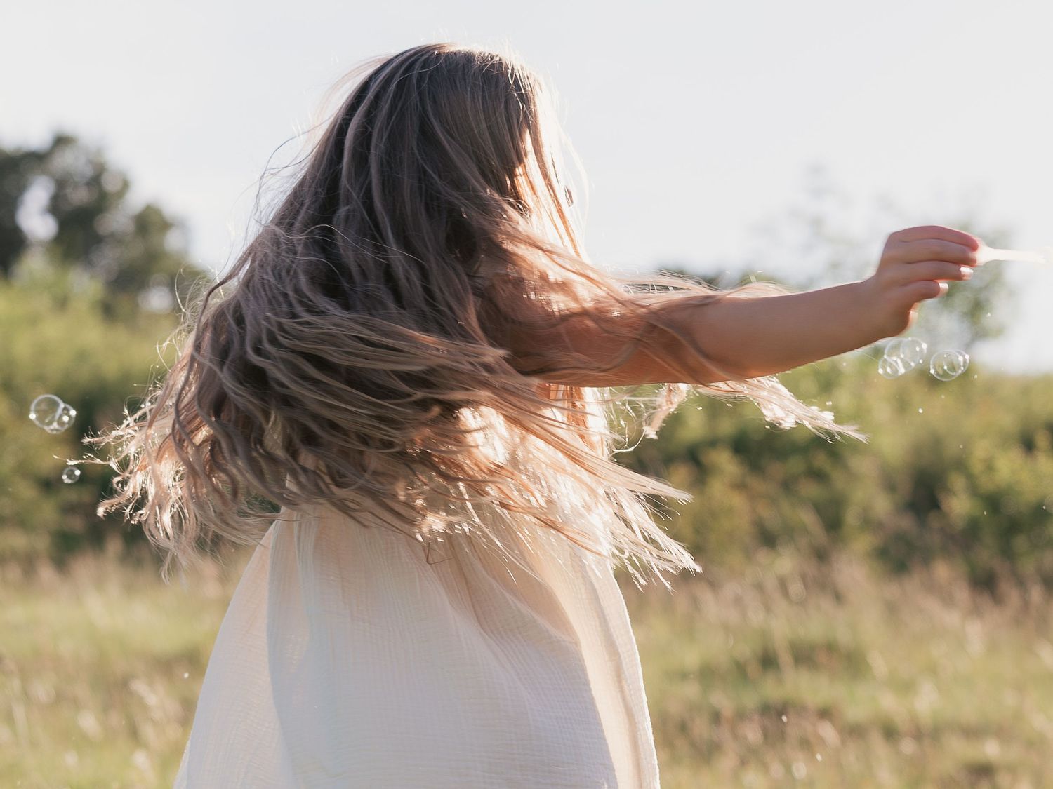 Child twirling and swishing long hair at golden hour