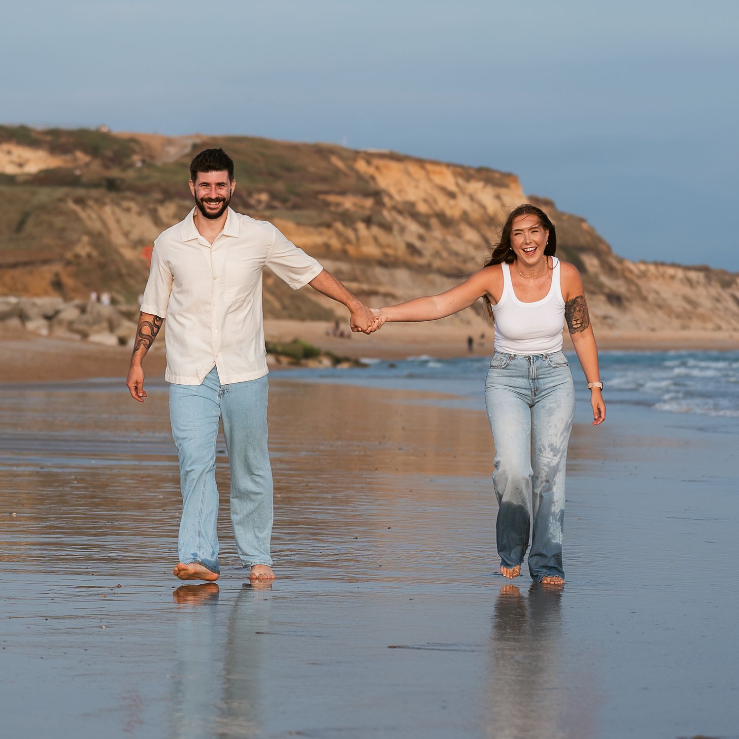 Engaged couple walking at the beach laughing