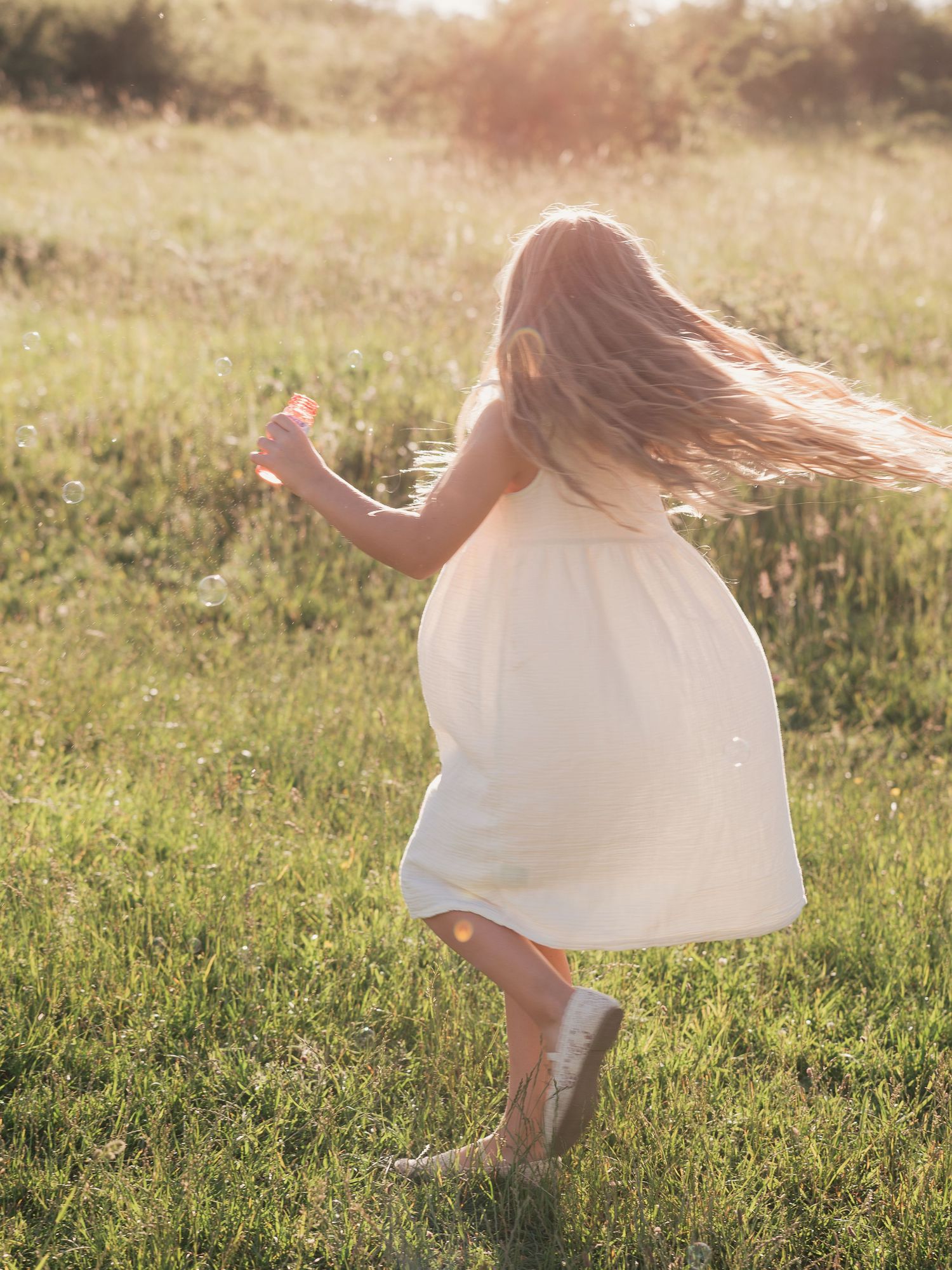 girl at golden hour running through field