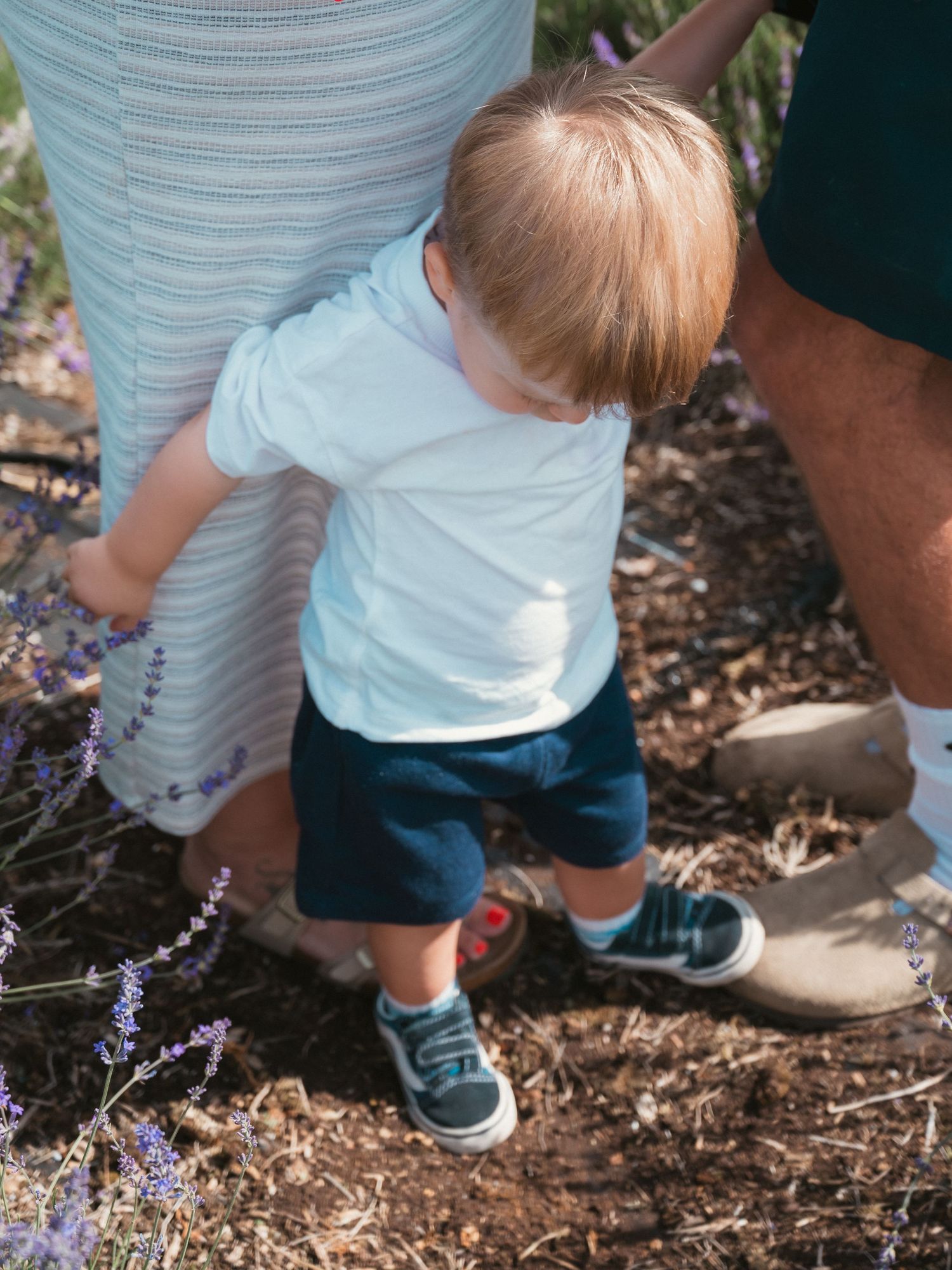 Toddler holding on to mum and looking down at all feet