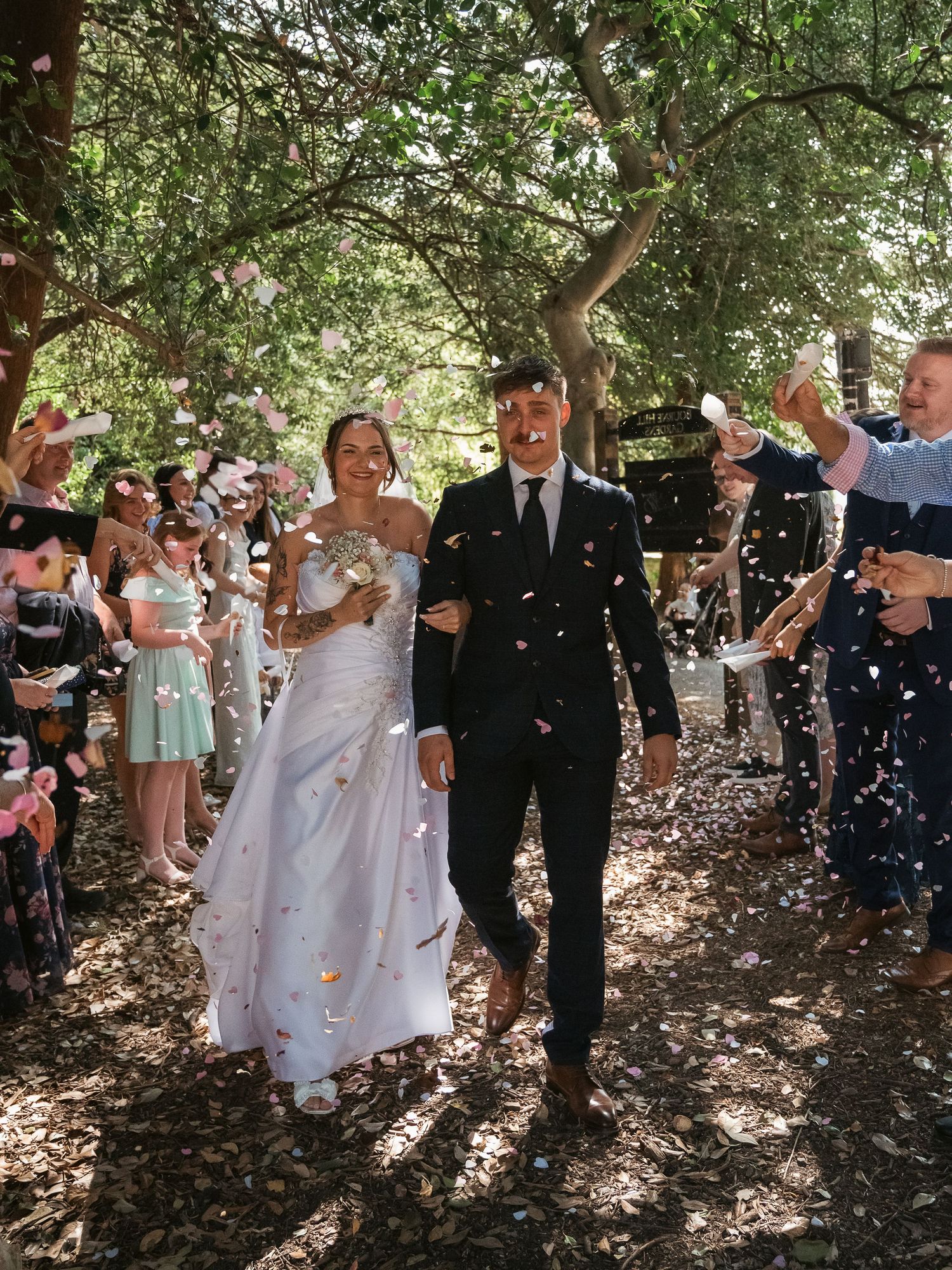 Confetti shot of bride and groom walking through trees