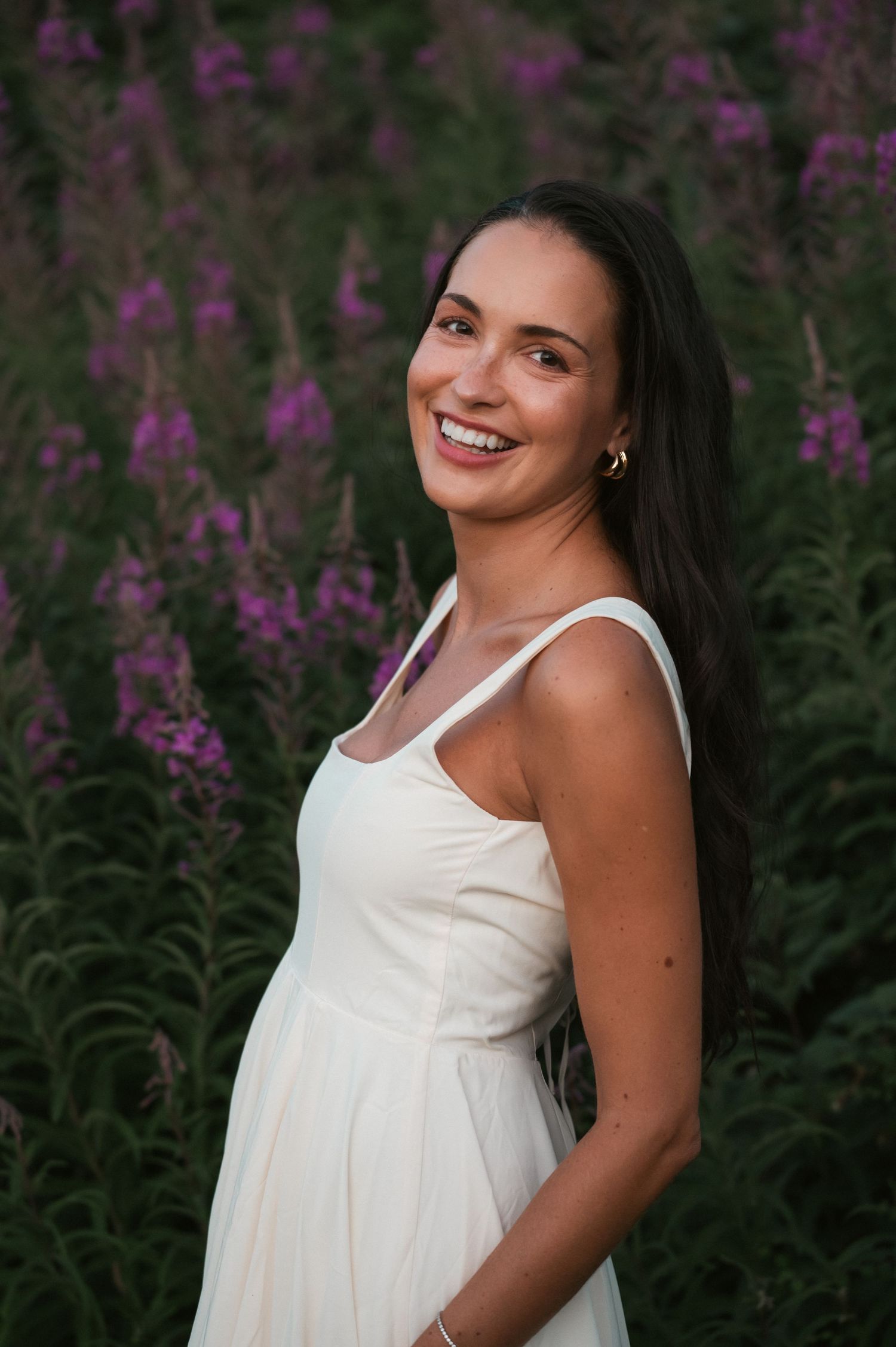 Portrait shot of model in white dress amongst purple flowers