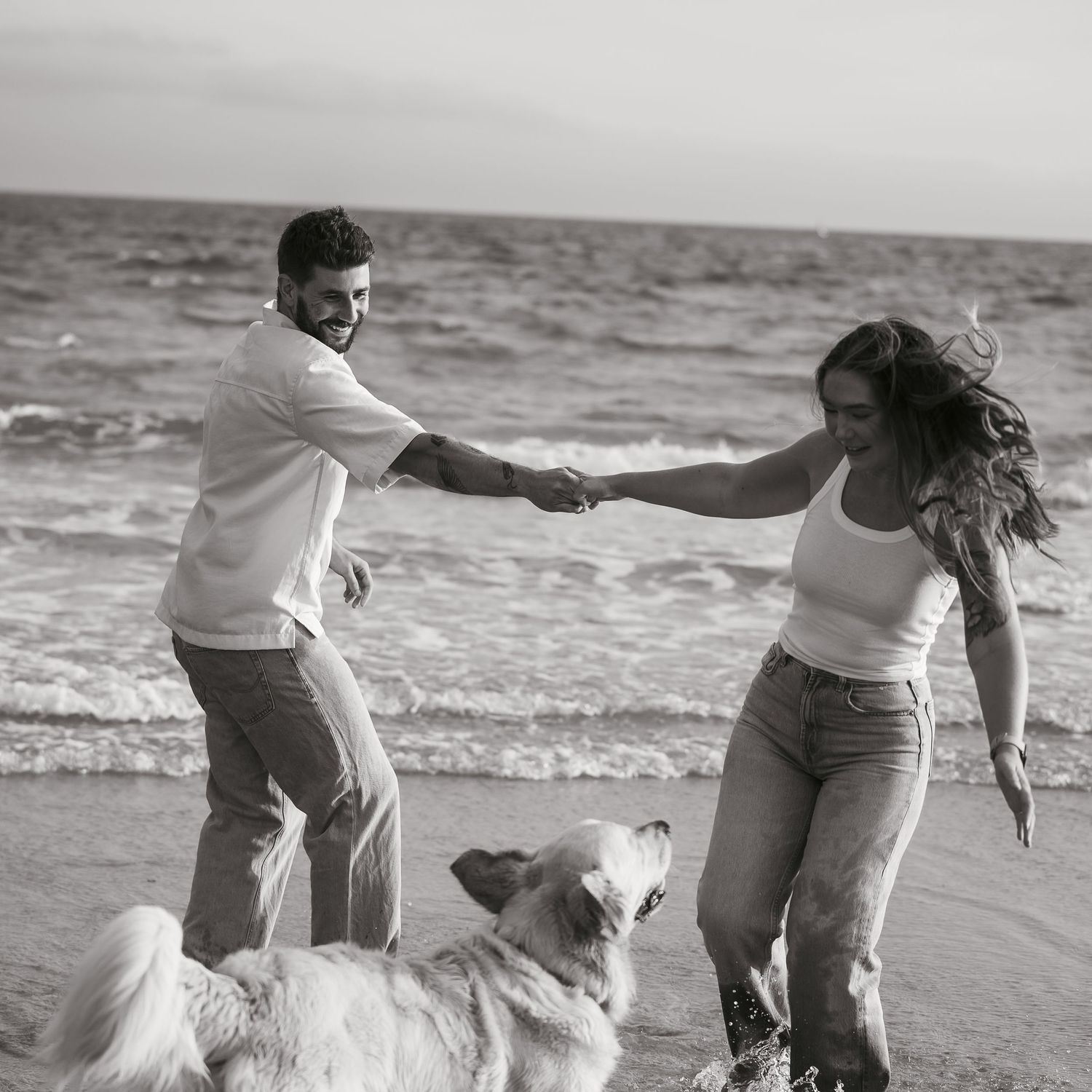 Couple at the beach with their dog playing