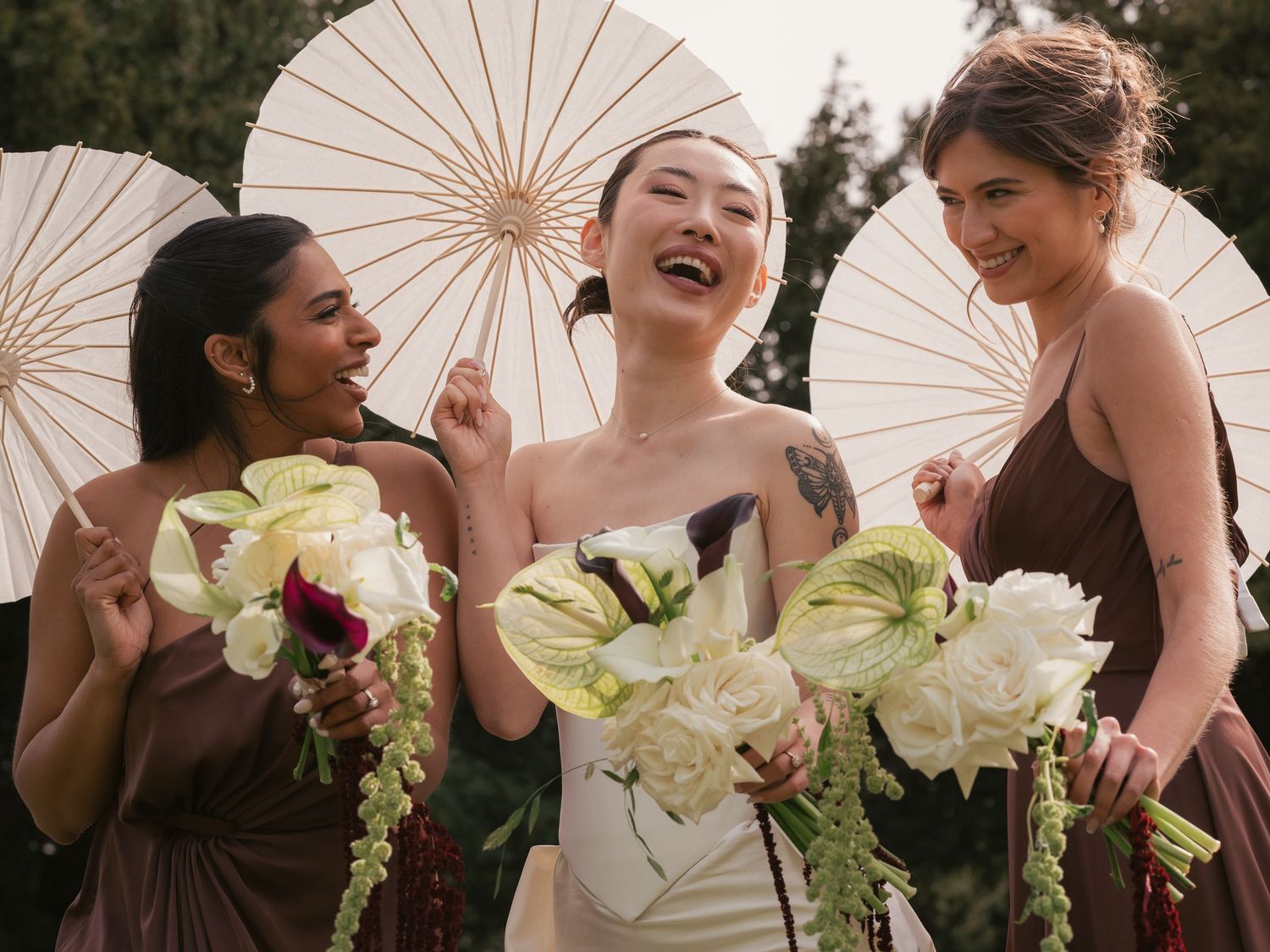 bride and bridesmaids laughing with bouquets