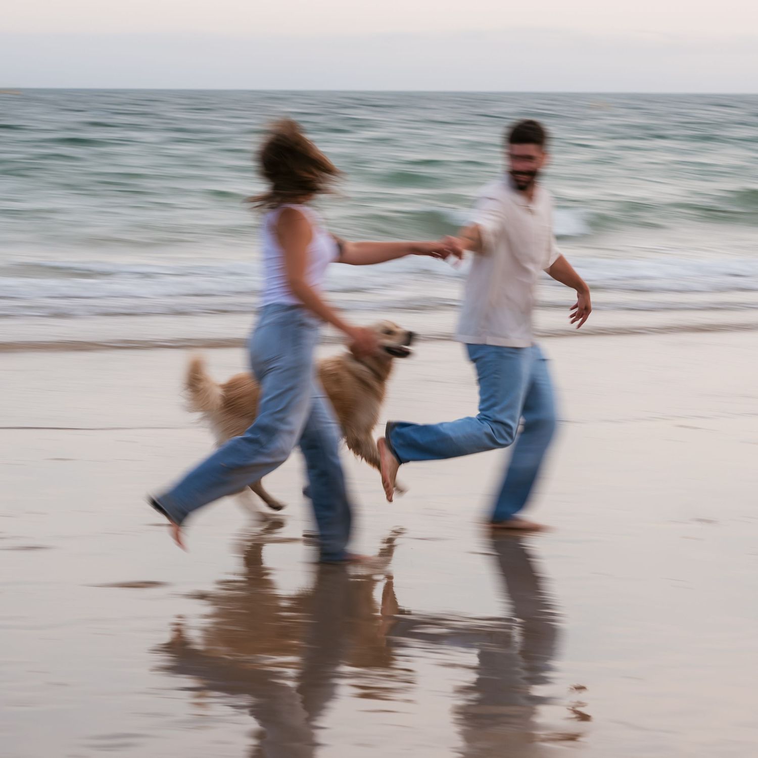 Motion blur of couple and their dog at the beach running