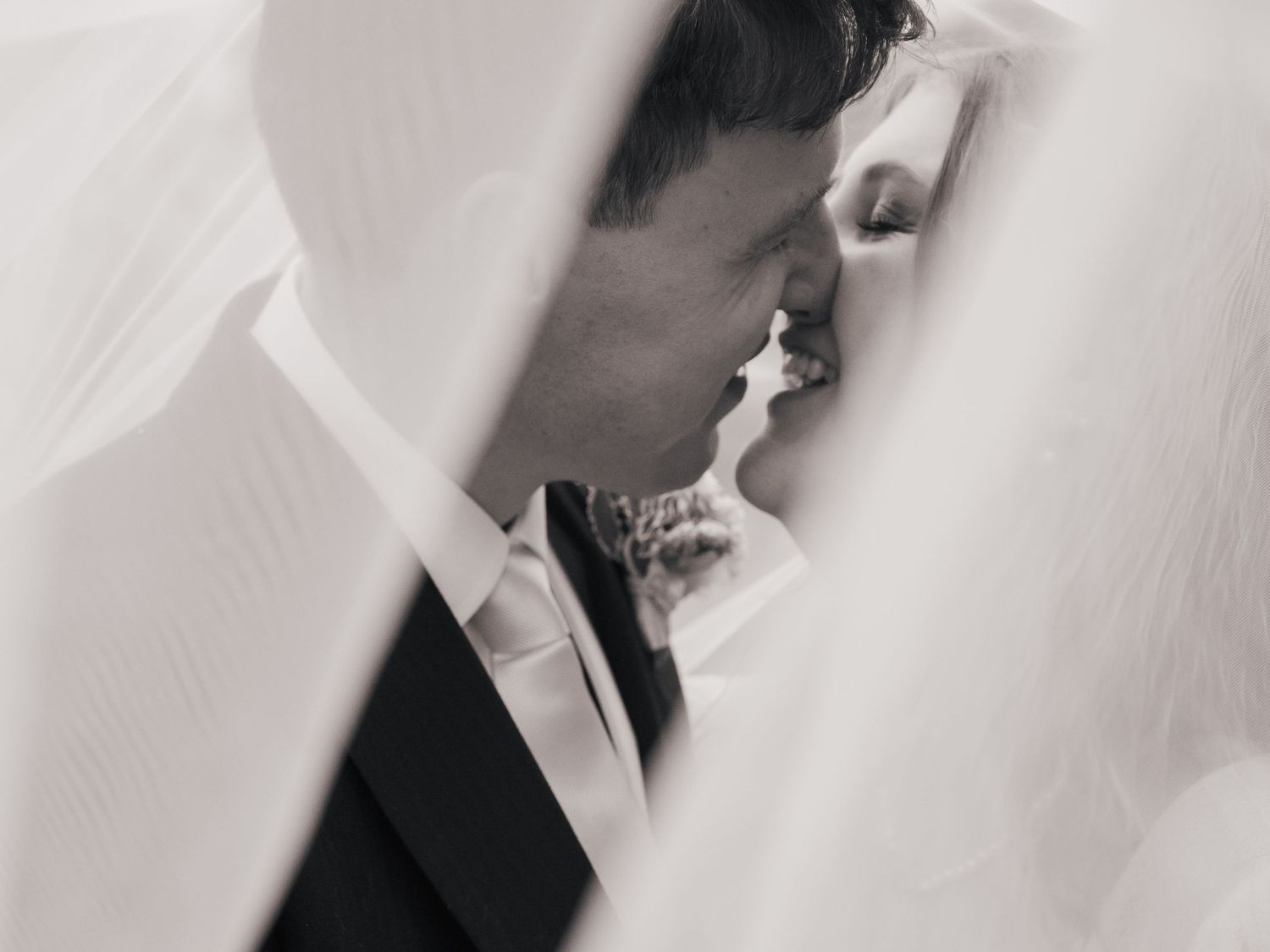 veil shot of bride and groom about to kiss and smiling